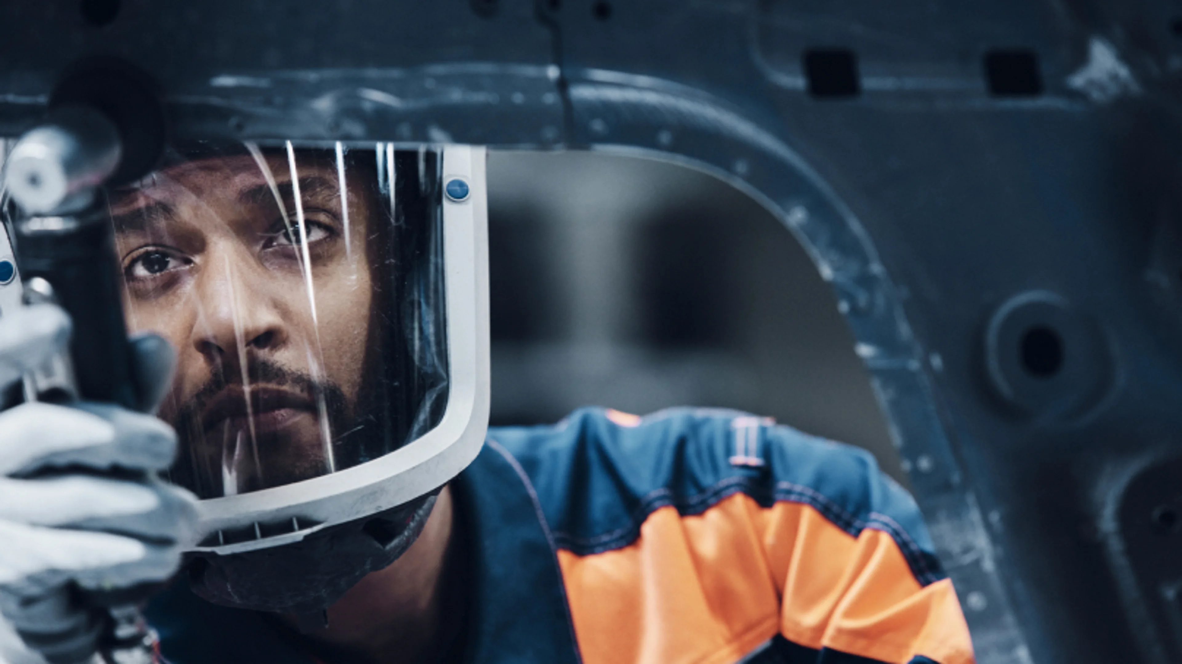 A man wearing a safety helmet working on some part.
