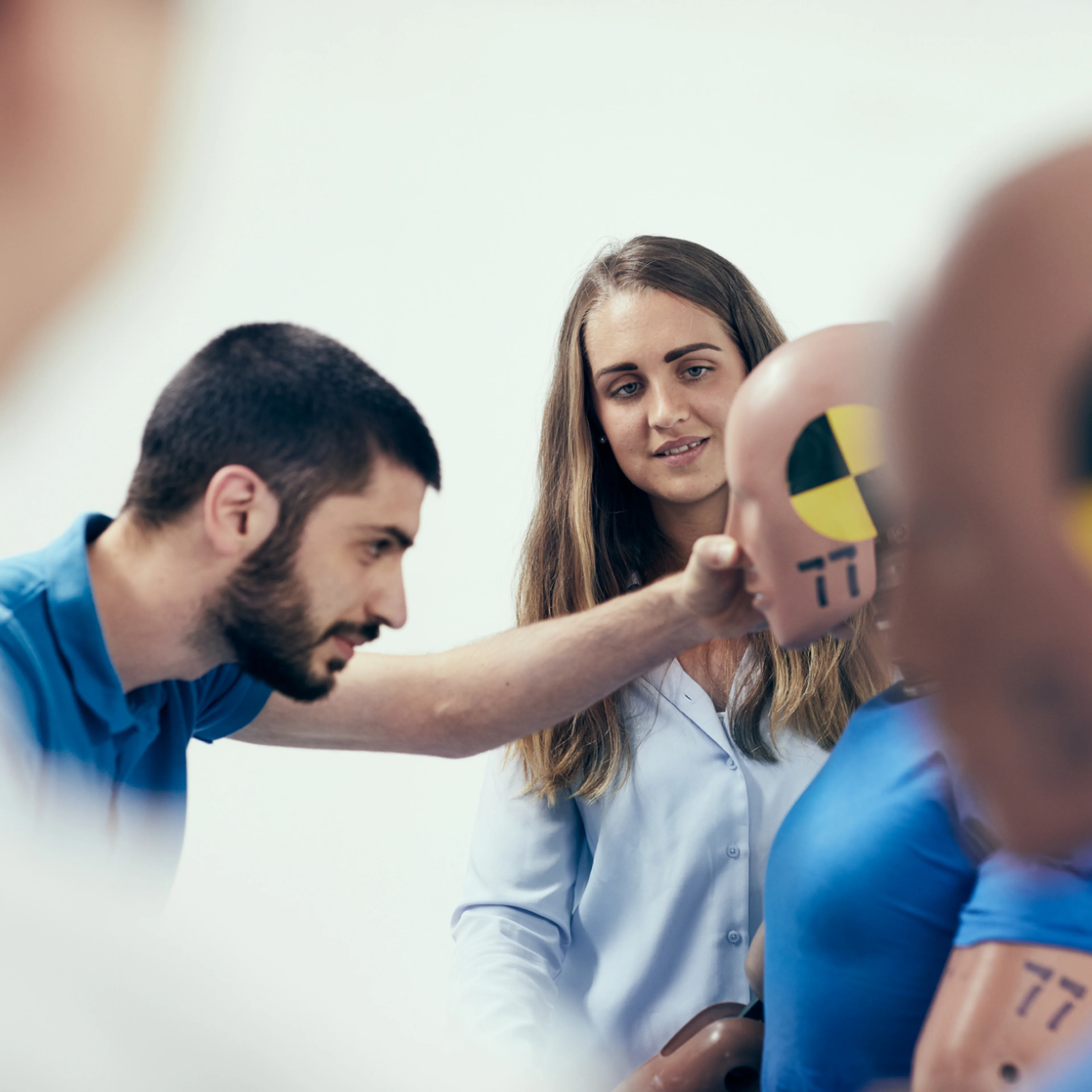 Un bărbat inspectând un manechin pentru teste de impact, în timp ce o femeie observă.