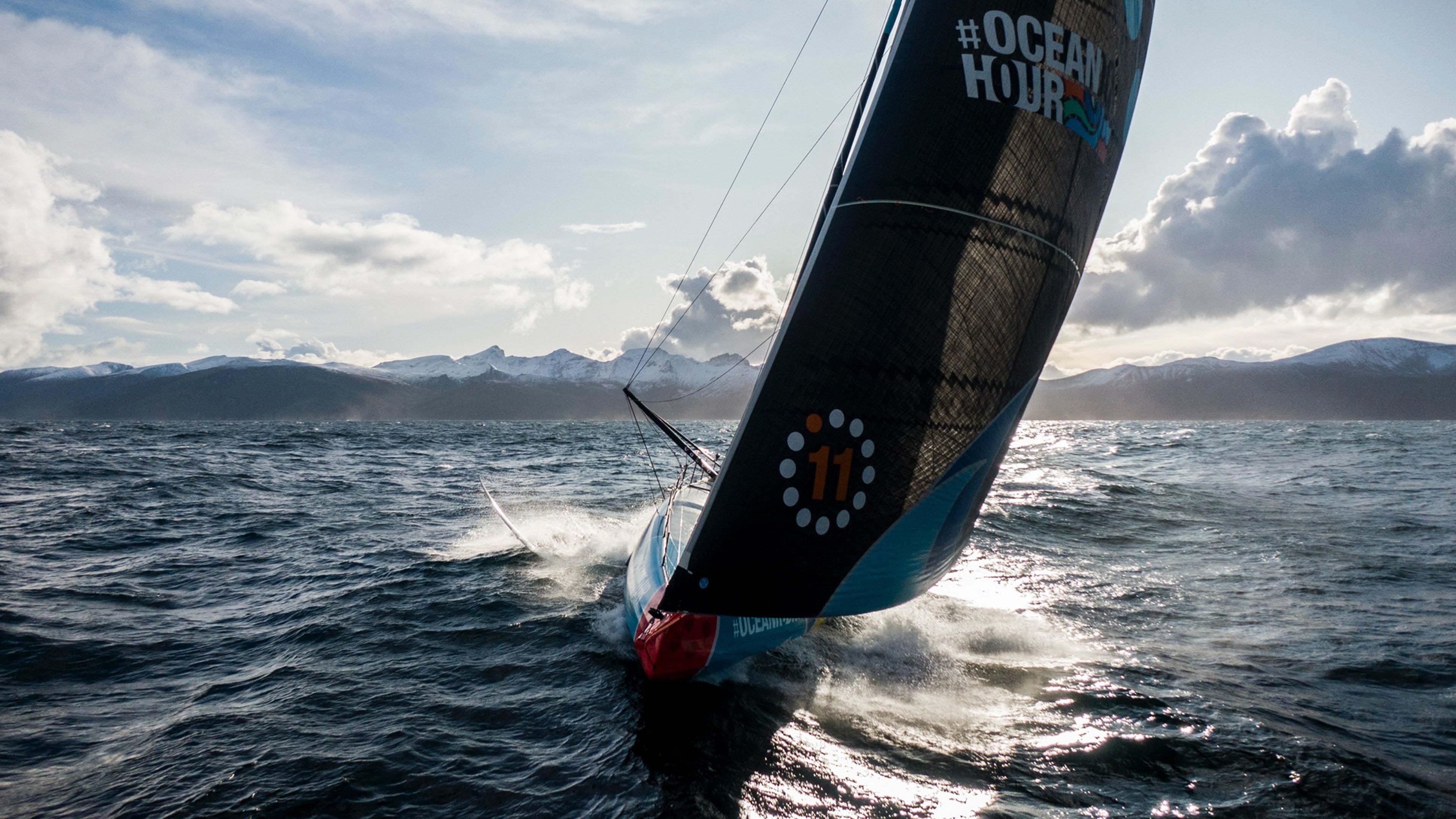 Visokoperformansna jedrilica koja juri kroz otvorene okeanske vode pod dramatičnim nebom, sa oznakama The Ocean Race.