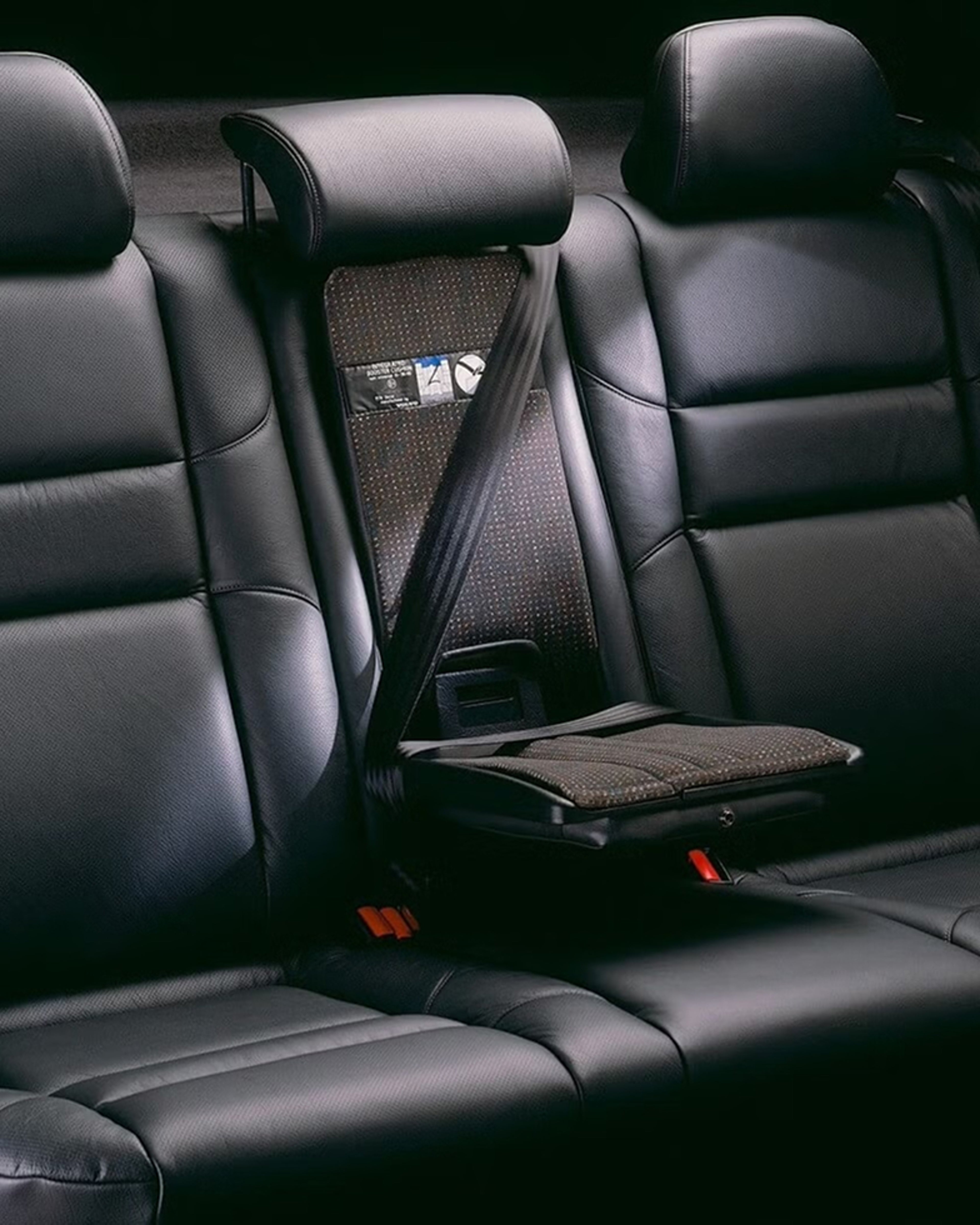 A raised integrated booster cushion in the centre rear seat of a black leather Volvo car interior.
