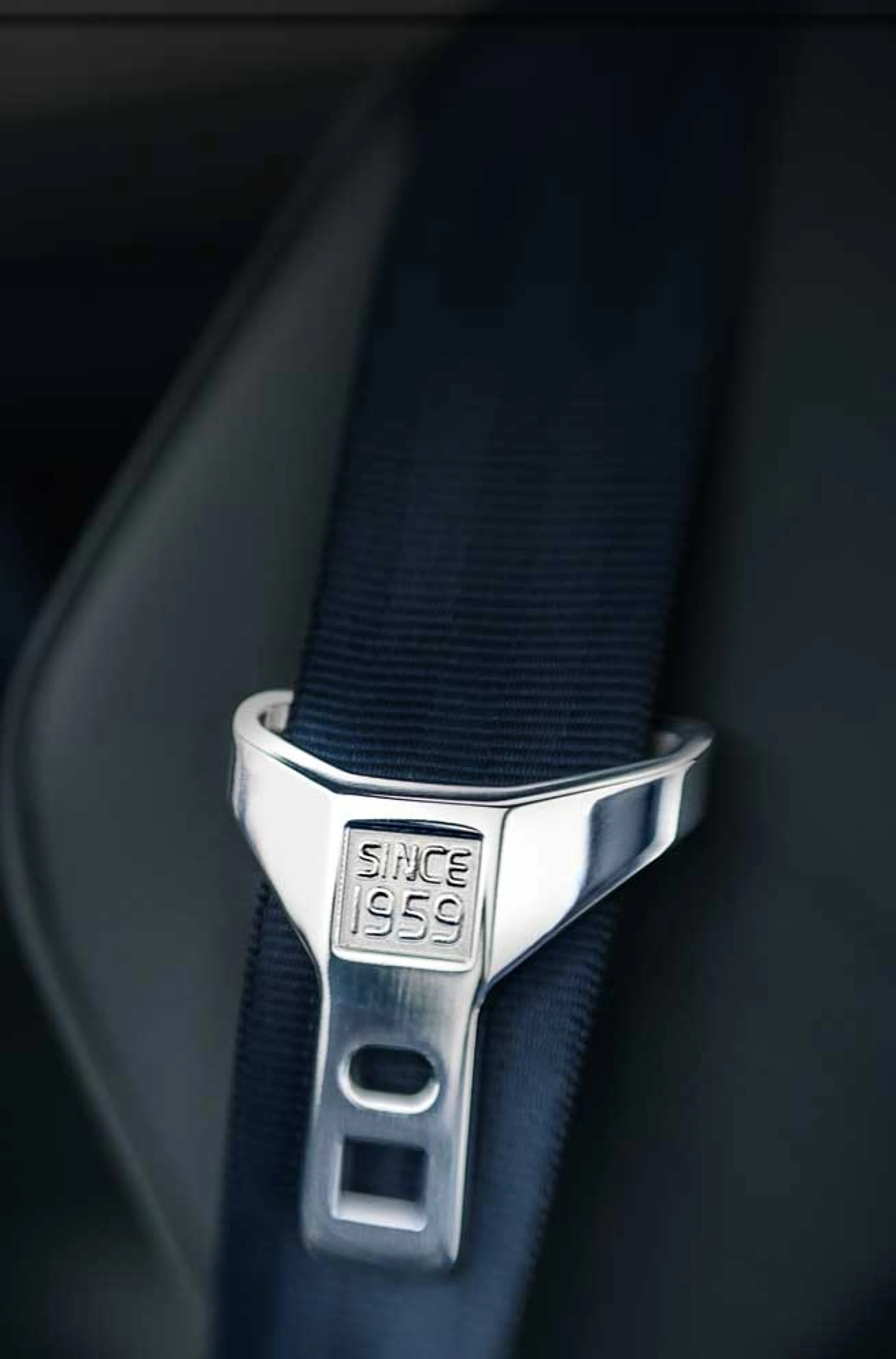 Ceinture de sécurité grise avec le texte « Depuis 1959 » gravé sur la boucle.