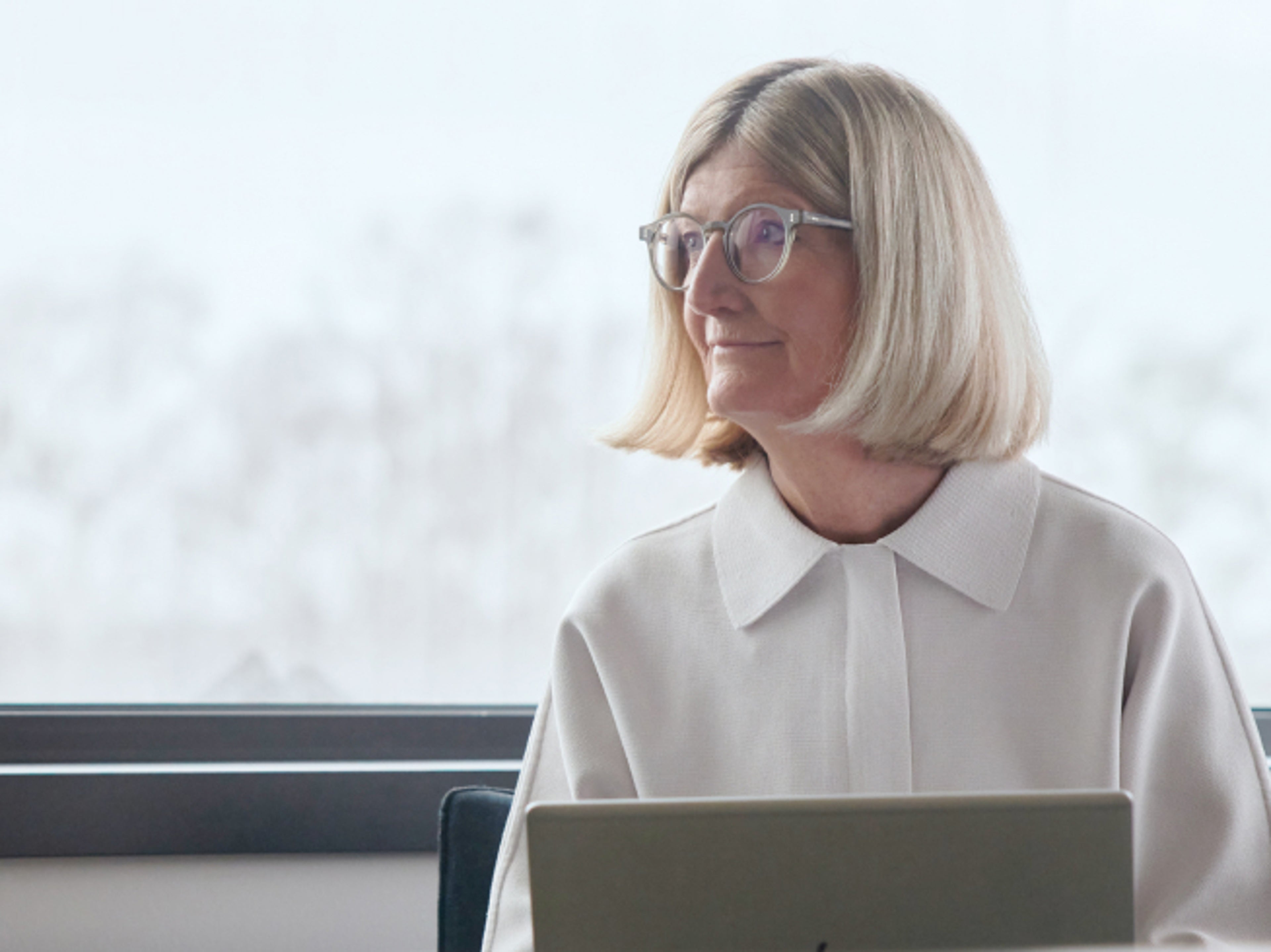 An elderly lady with what looks like a laptop gazing to her right.