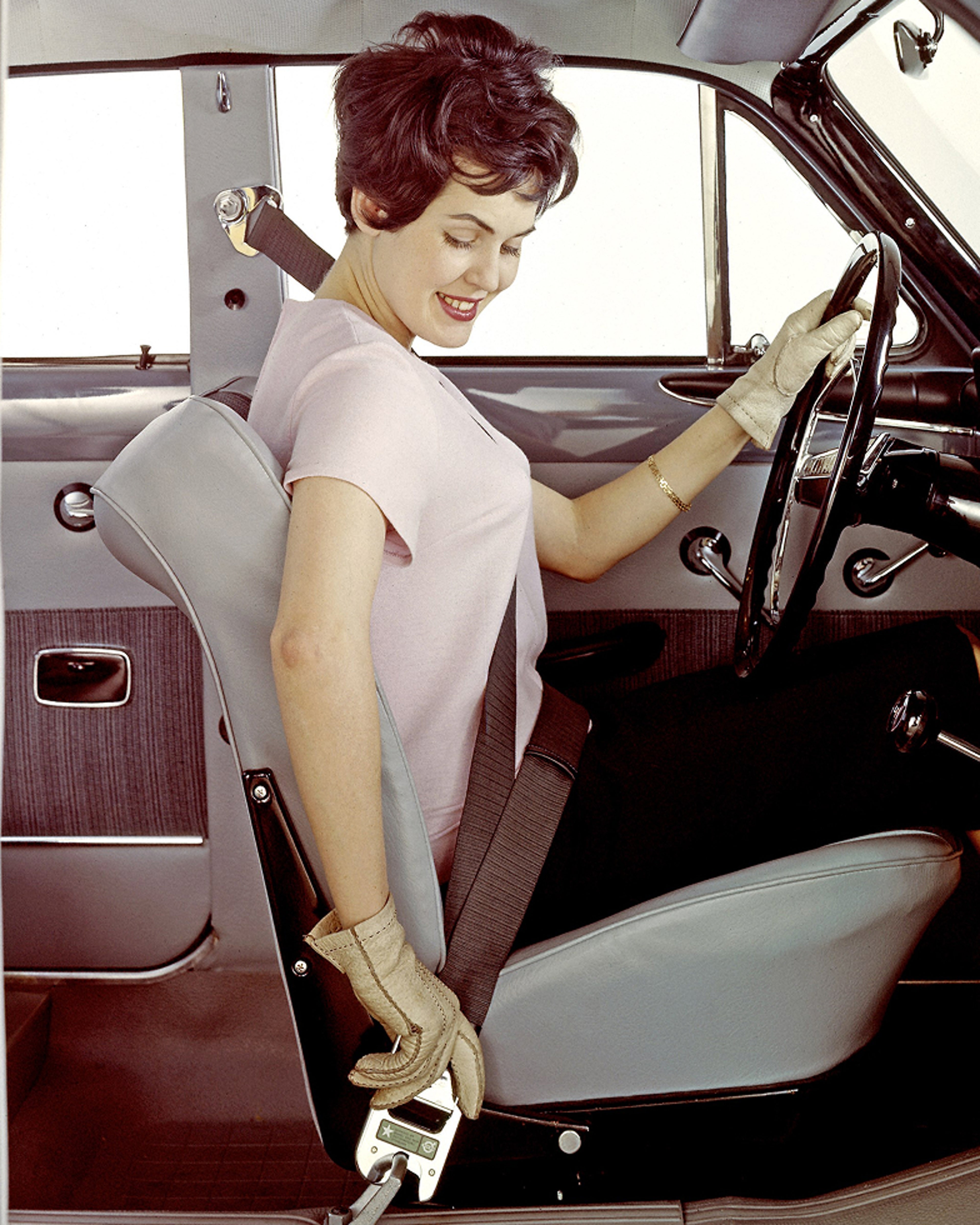 A woman fastening a three-point safety belt in a Volvo PV544, illustrating the introduction of Nils Bohlin’s design.