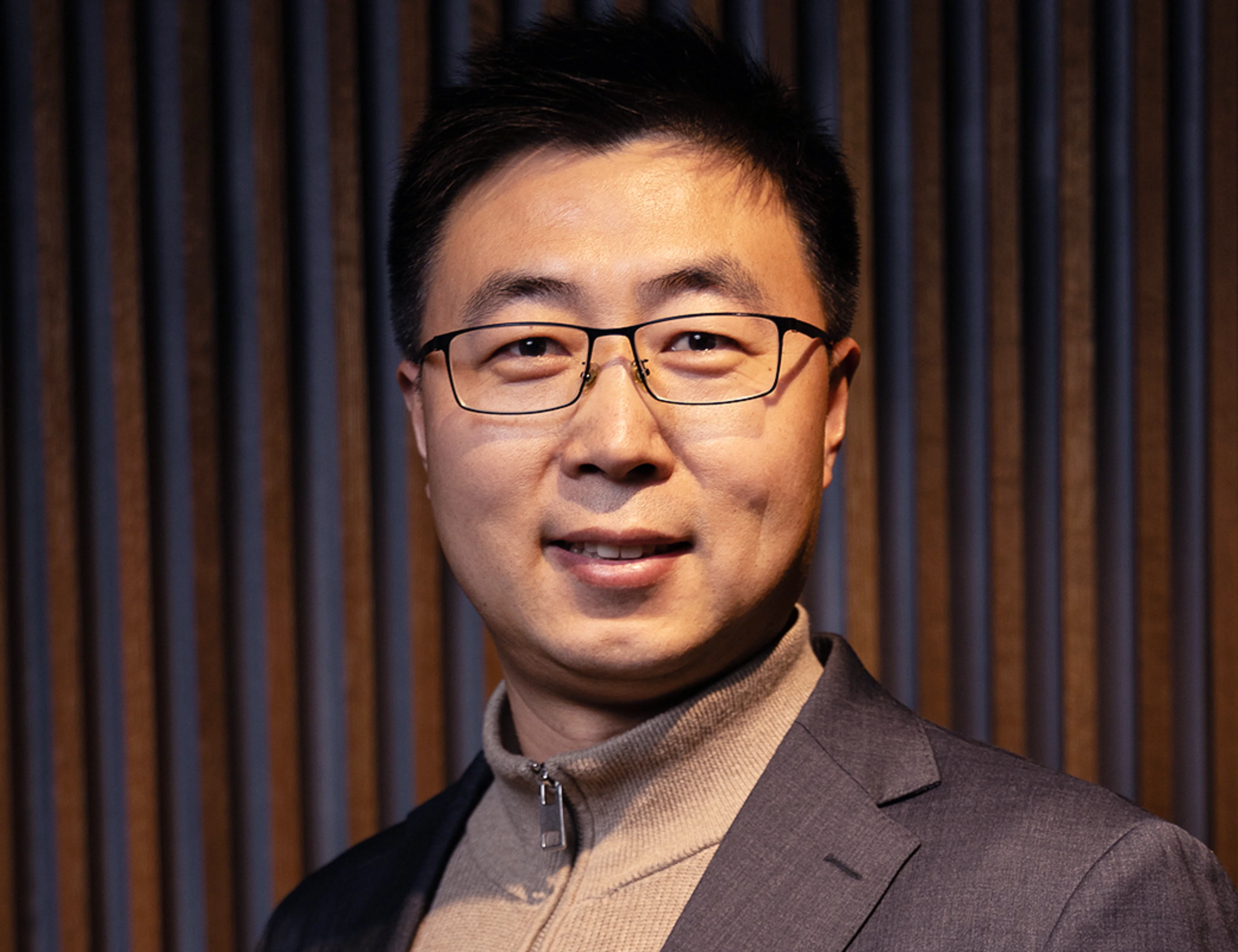 A portrait photo of a man with eye-glasses.