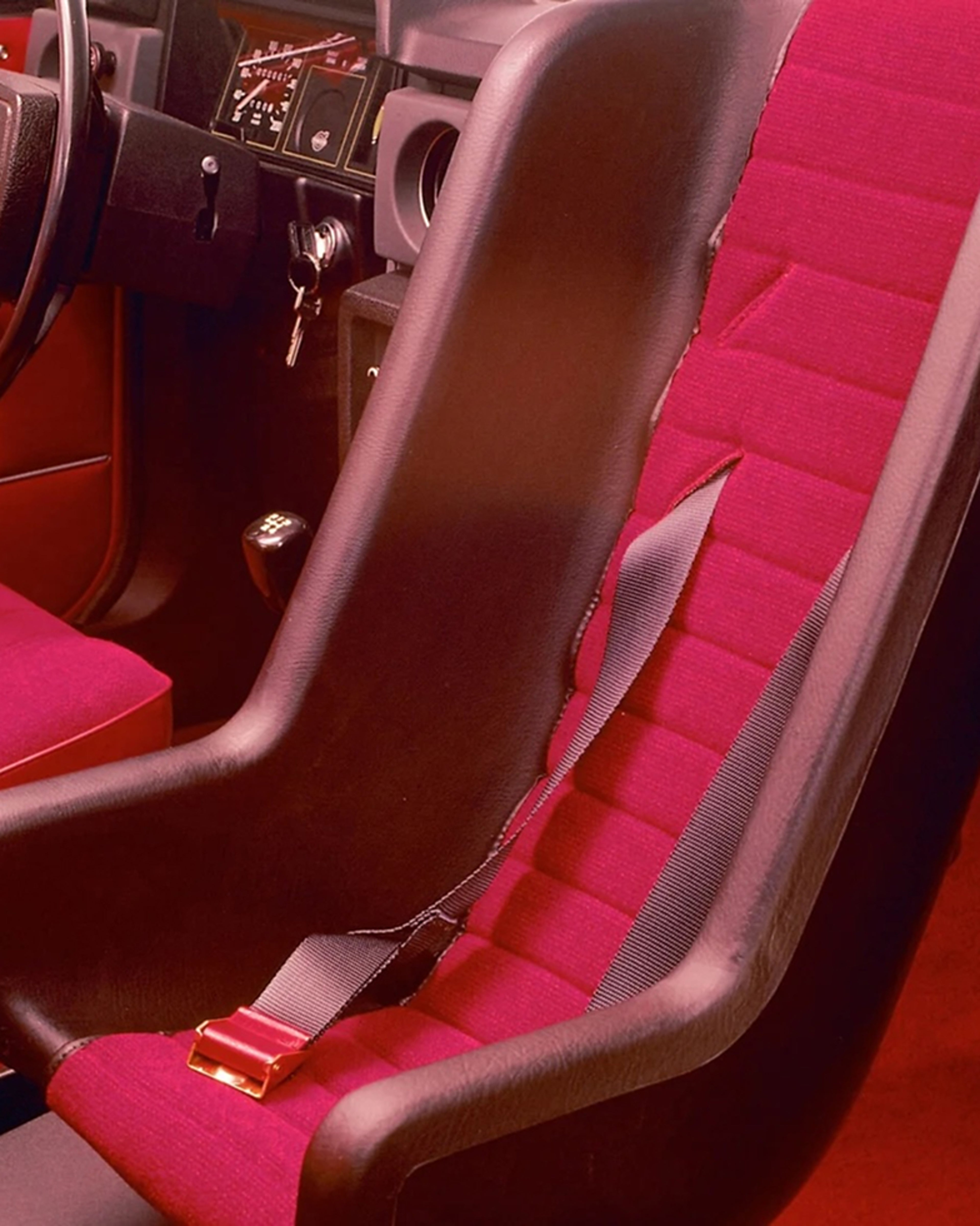 A red rear-facing child seat installed in the front passenger seat of a Volvo car, showcasing Volvo’s 1972 innovation.