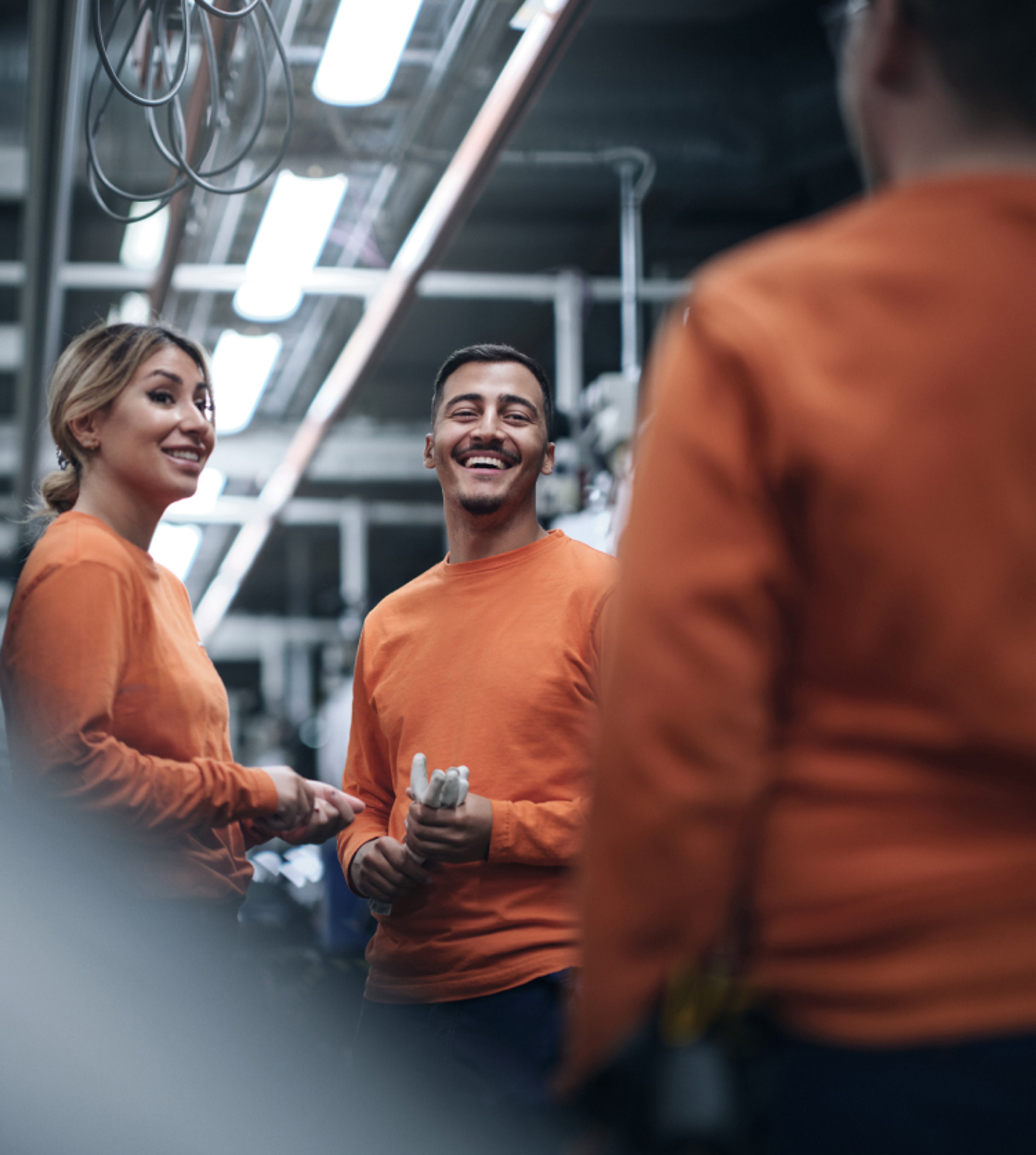 Drei Personen unterhalten sich in einem Fertigungswerk.