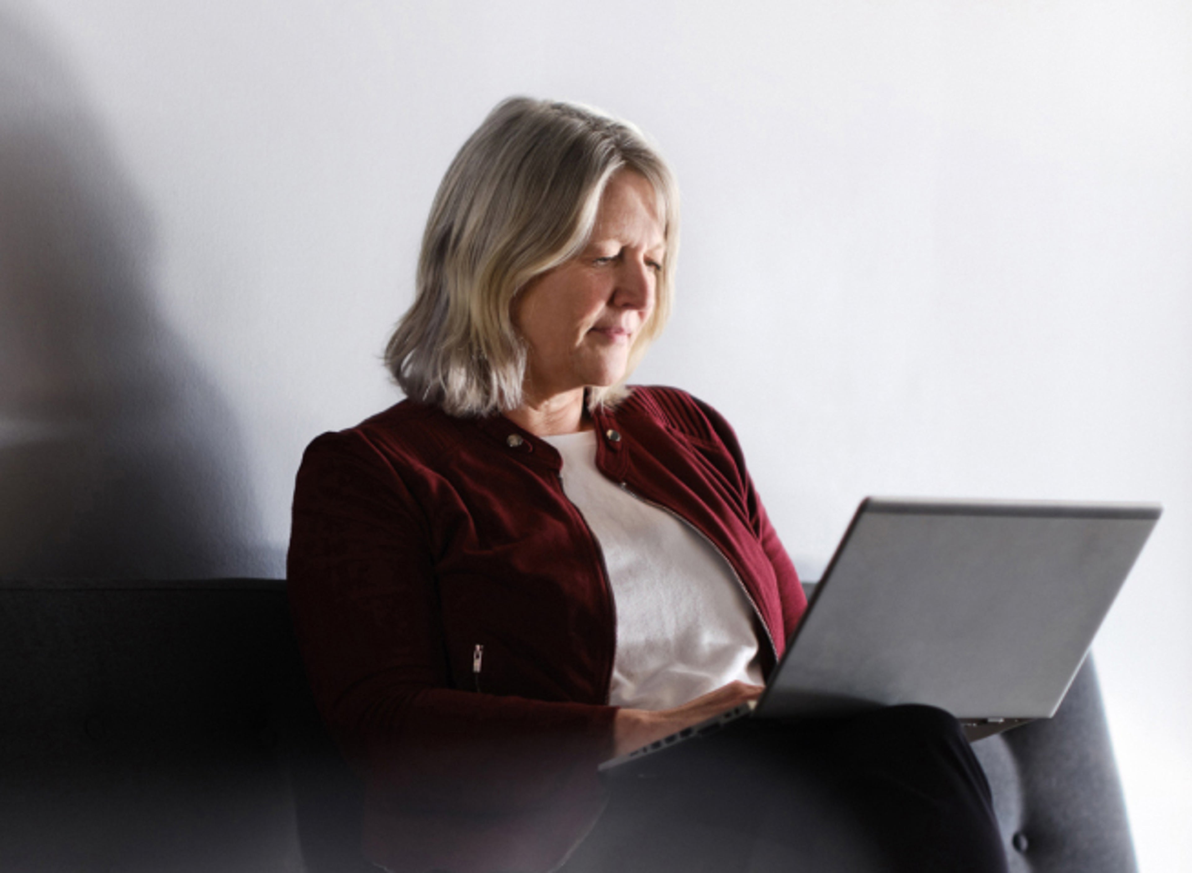 A woman on a black sofa using a laptop