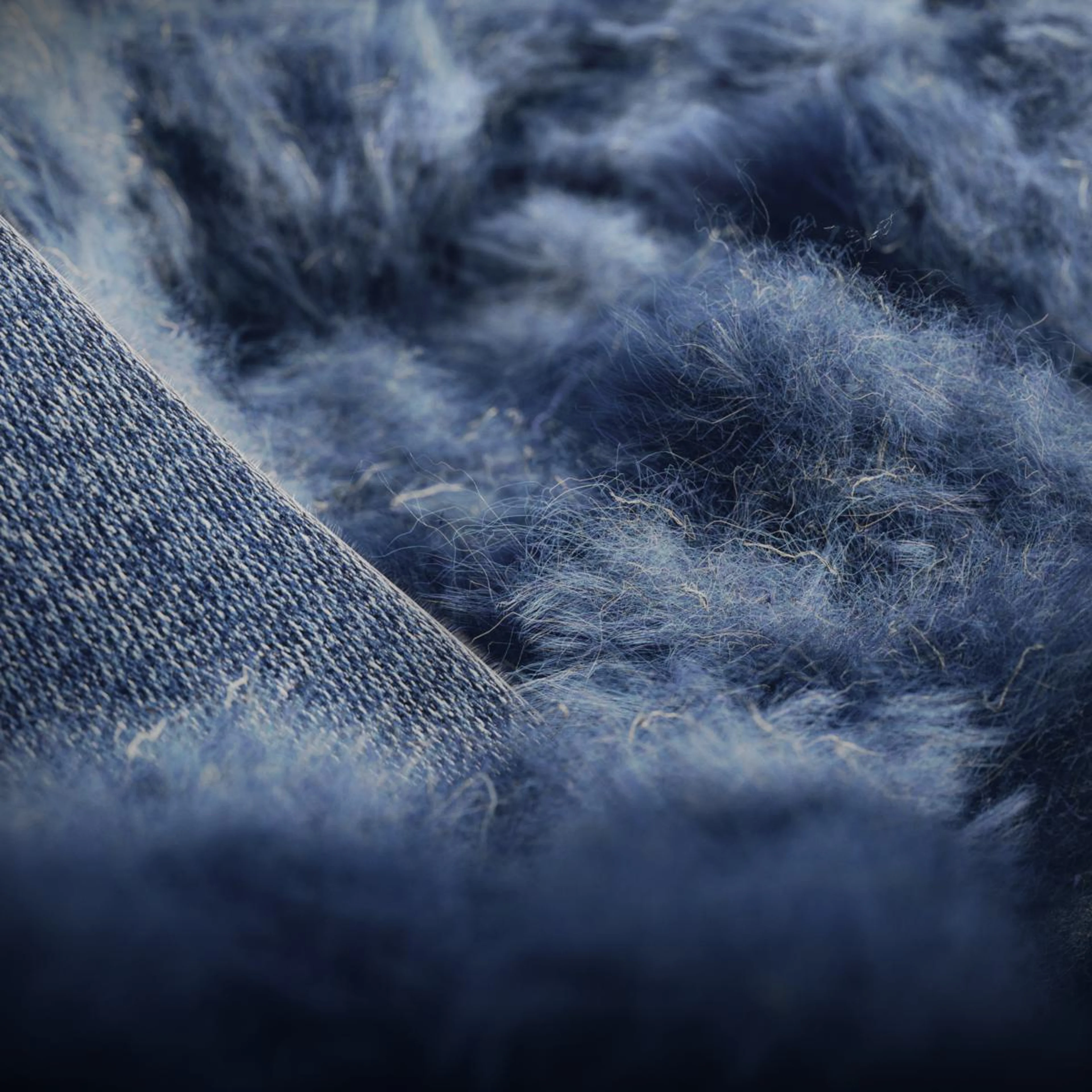 Gros plan sur les fibres de denim bleues, soulignant l’utilisation par Volvo de fibres courtes issues de jeans recyclés pour créer des décors intérieurs en denim dans le cadre de ses initiatives de développement durable.