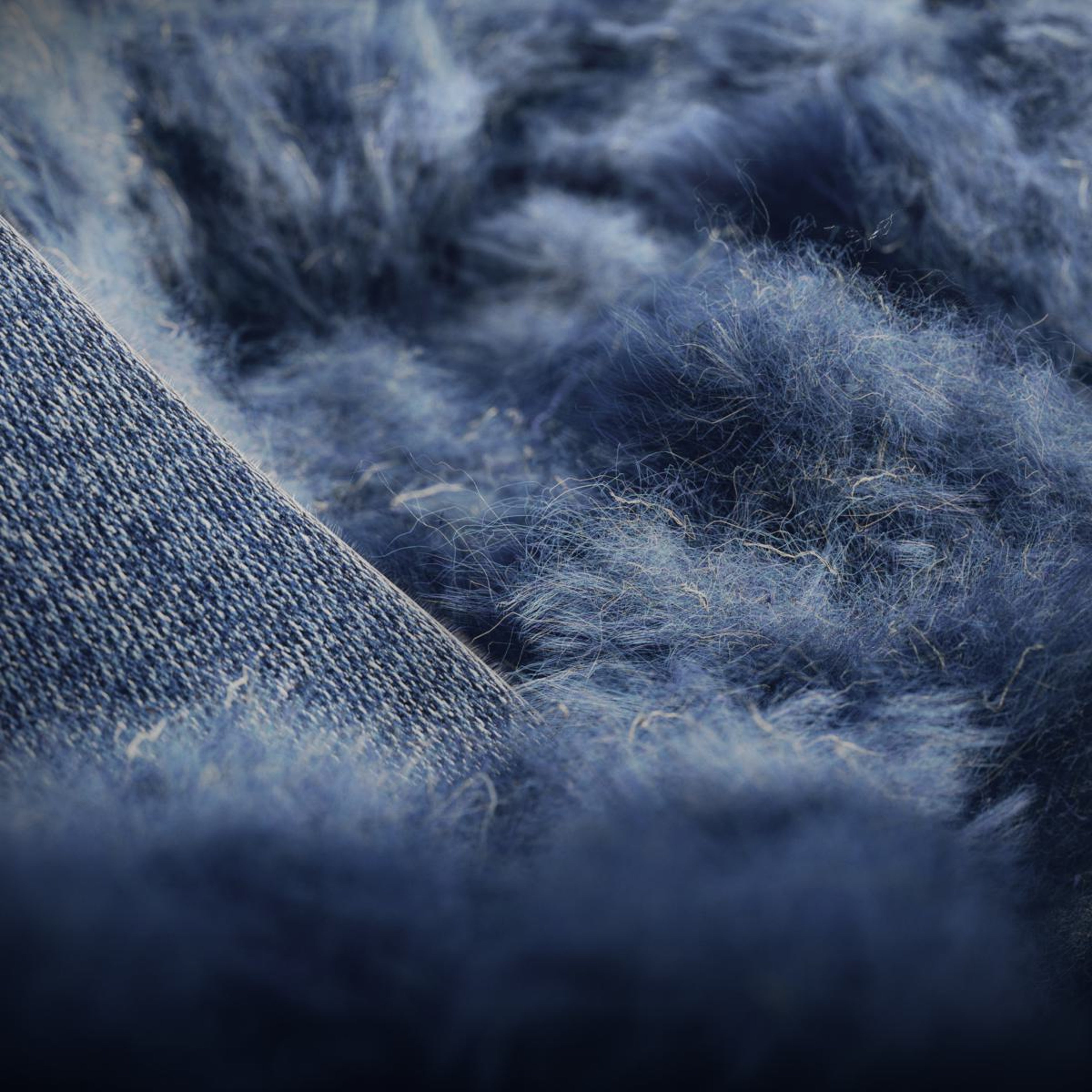 Gros plan sur les fibres de denim bleues, soulignant l’utilisation par Volvo de fibres courtes issues de jeans recyclés pour créer des décors intérieurs en denim dans le cadre de ses initiatives de développement durable.