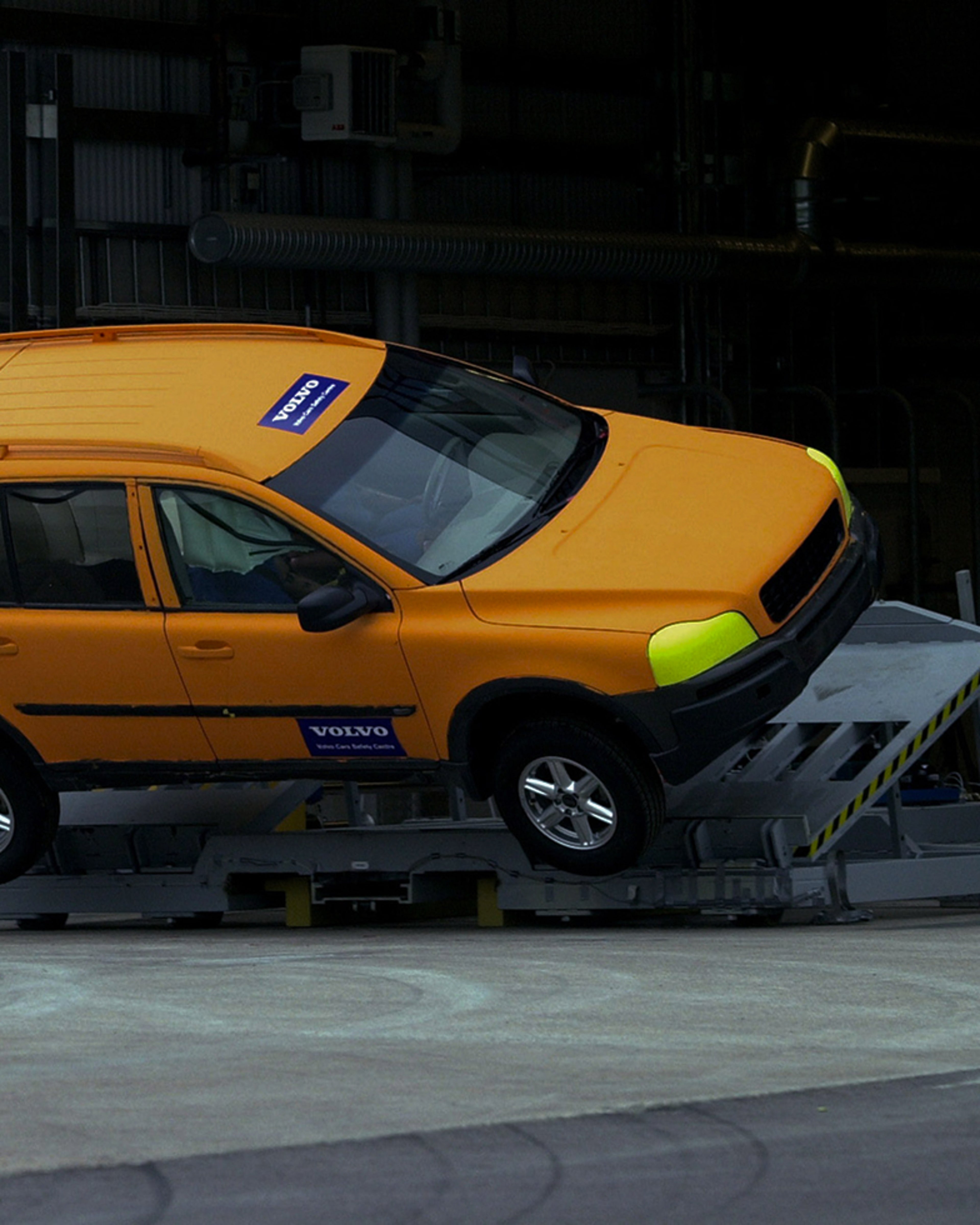 A bright orange Volvo SUV tilted on a test ramp, demonstrating the 2002 Rollover Occupant Protection System innovation.