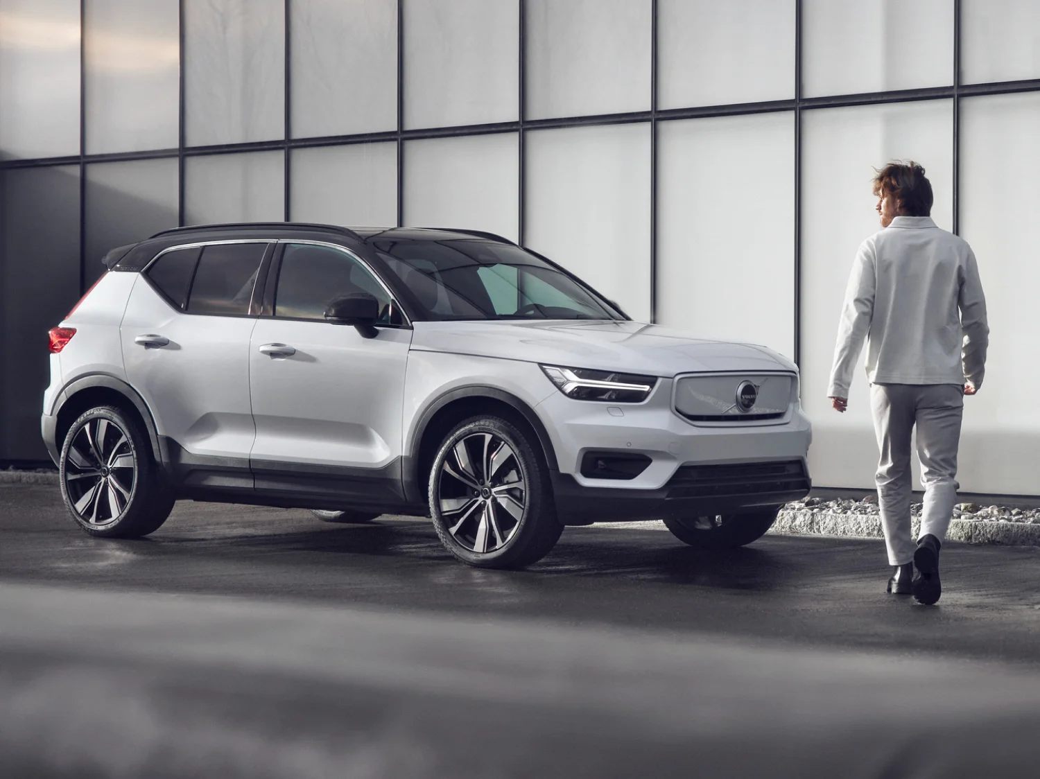 A man walking towards a parked Volvo XC40 fully electric car