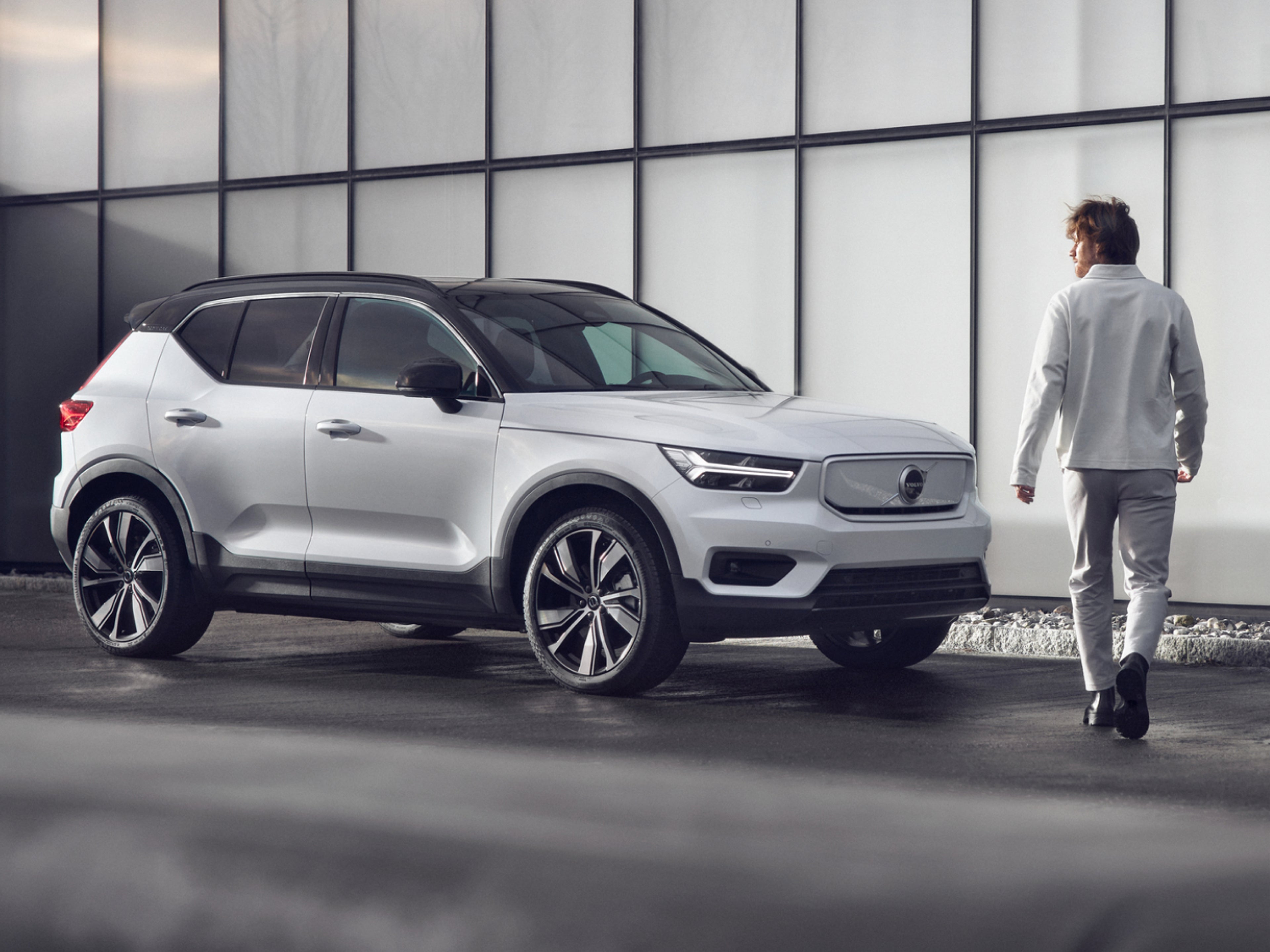 A man walking towards a parked Volvo XC40 fully electric car