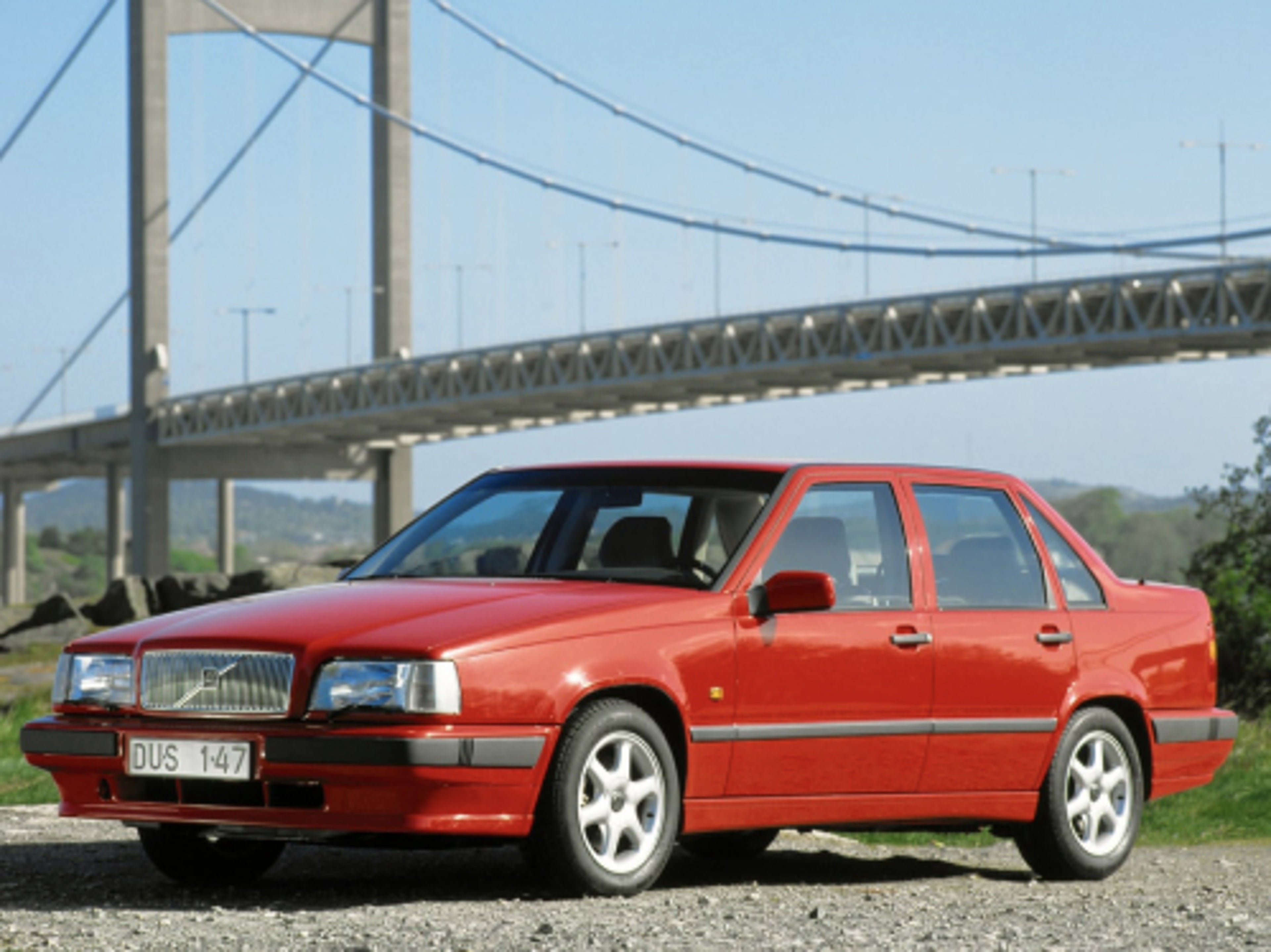 A red Volvo 850 standing in front of a bridge.