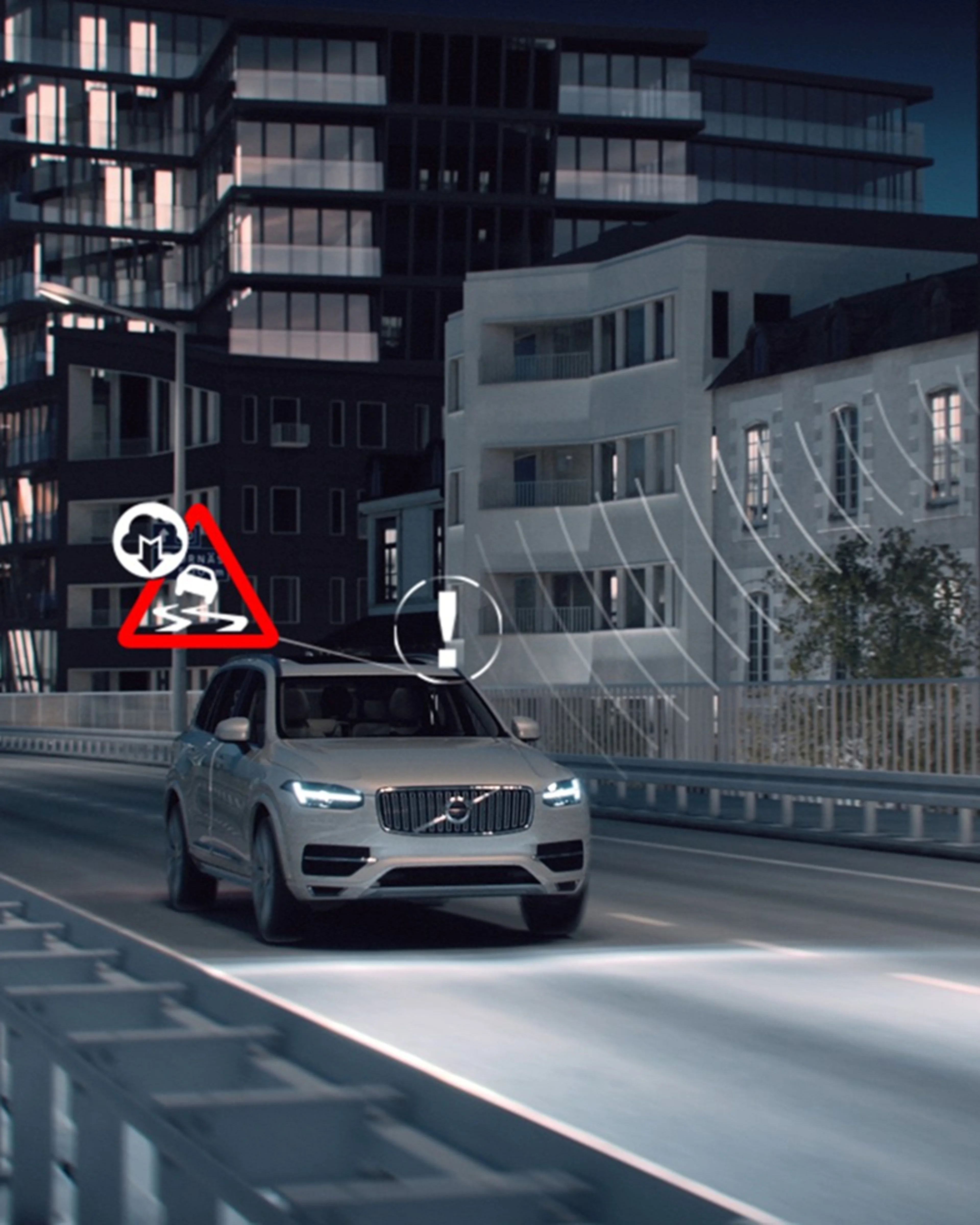 Srebreni Volvo SUV koji vozi noću na cesti s osvijetljenim ikonama opasnosti iznad automobila. Visoke zgrade u pozadini automobila.