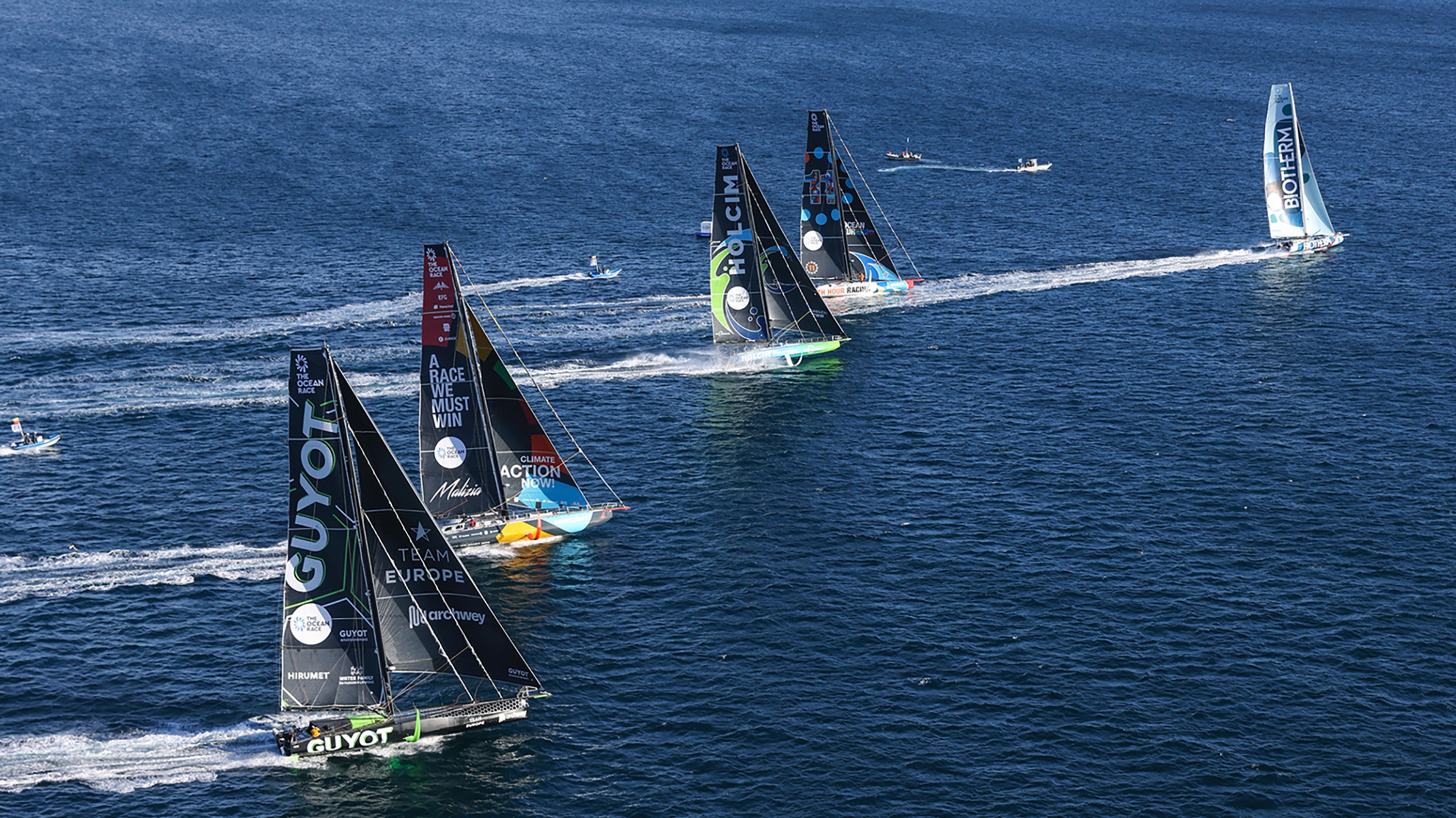 Flota trkačkih jahti koje učestvuju u regati The Ocean Race, jedreći u bliskoj formaciji preko otvorenog mora.