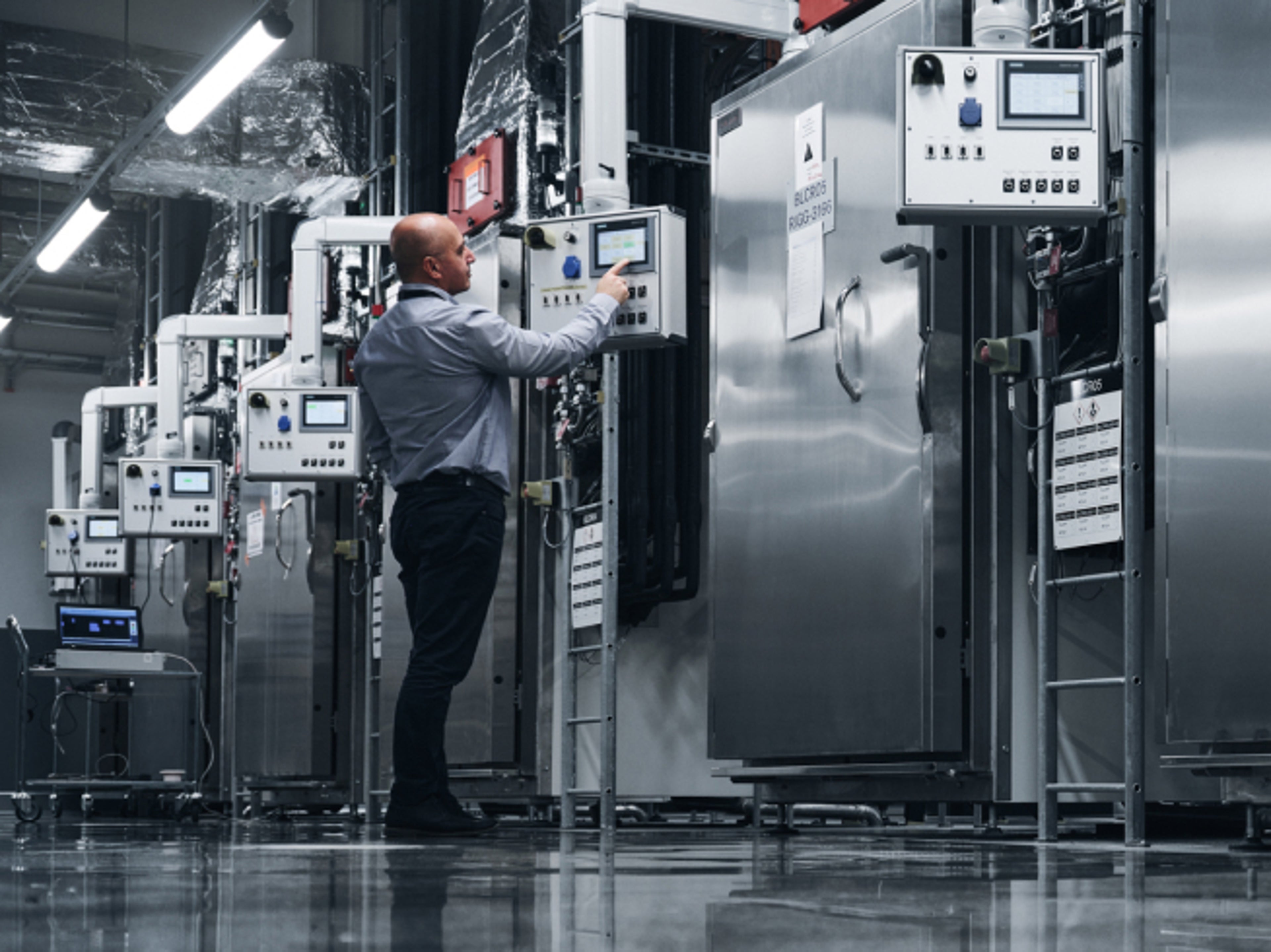 A man operating some system inside a manufacturing plant.