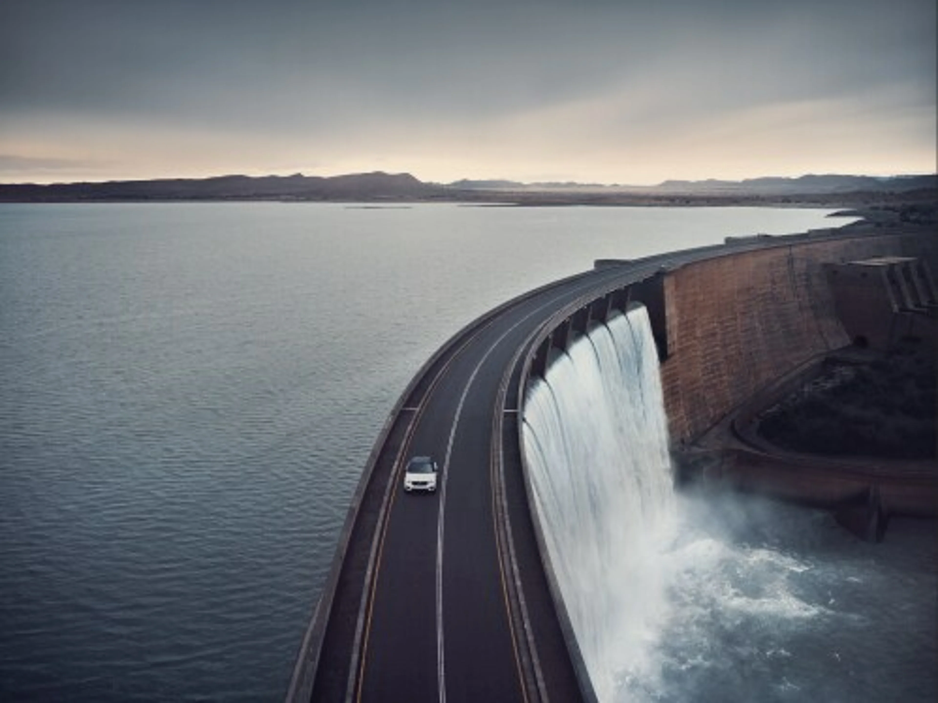 Volvo SUV ขับอยู่บนสะพานข้ามอ่างเก็บน้ำ