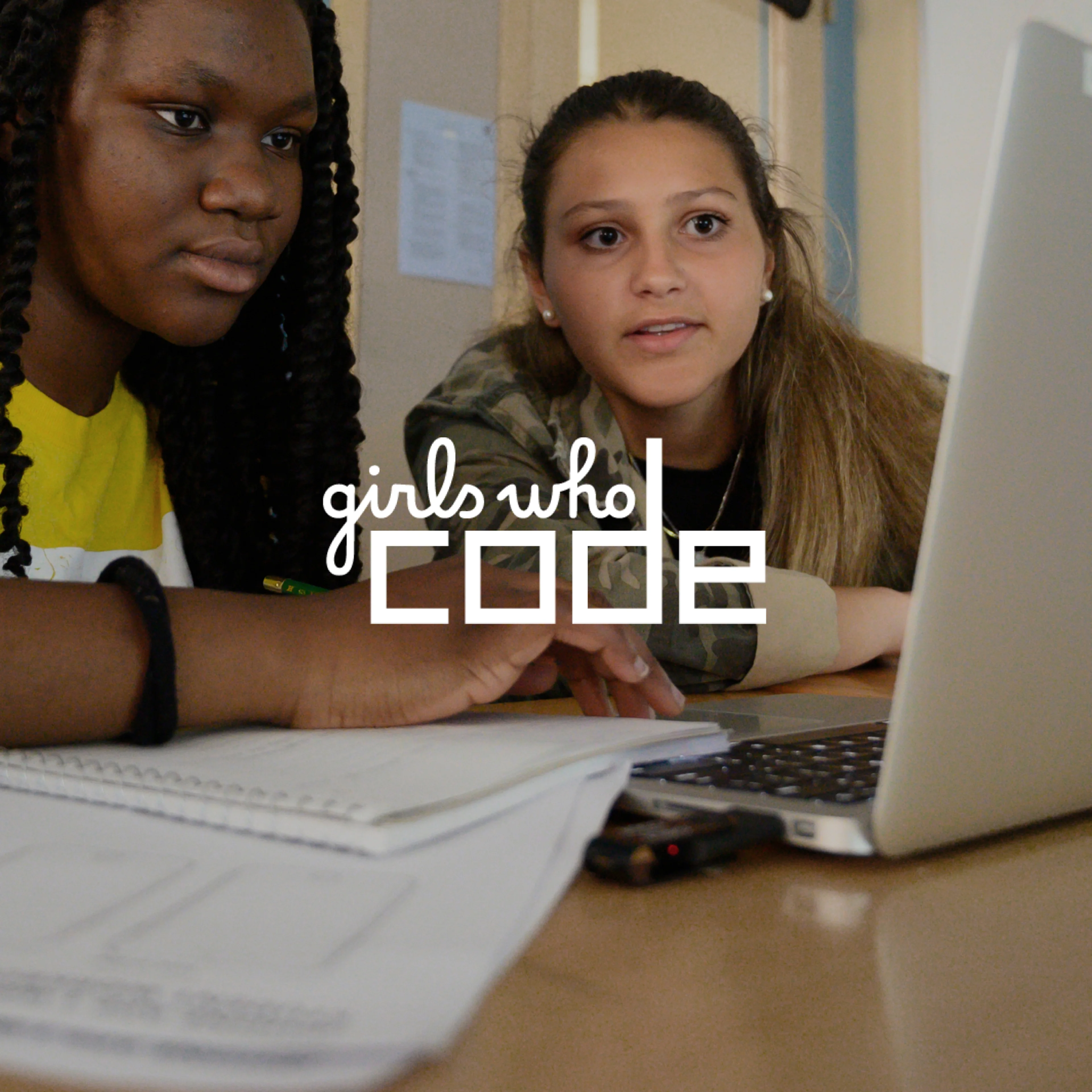 Two young girls learning to code on a computer with the text "Girls Who Code" overlaying the image.