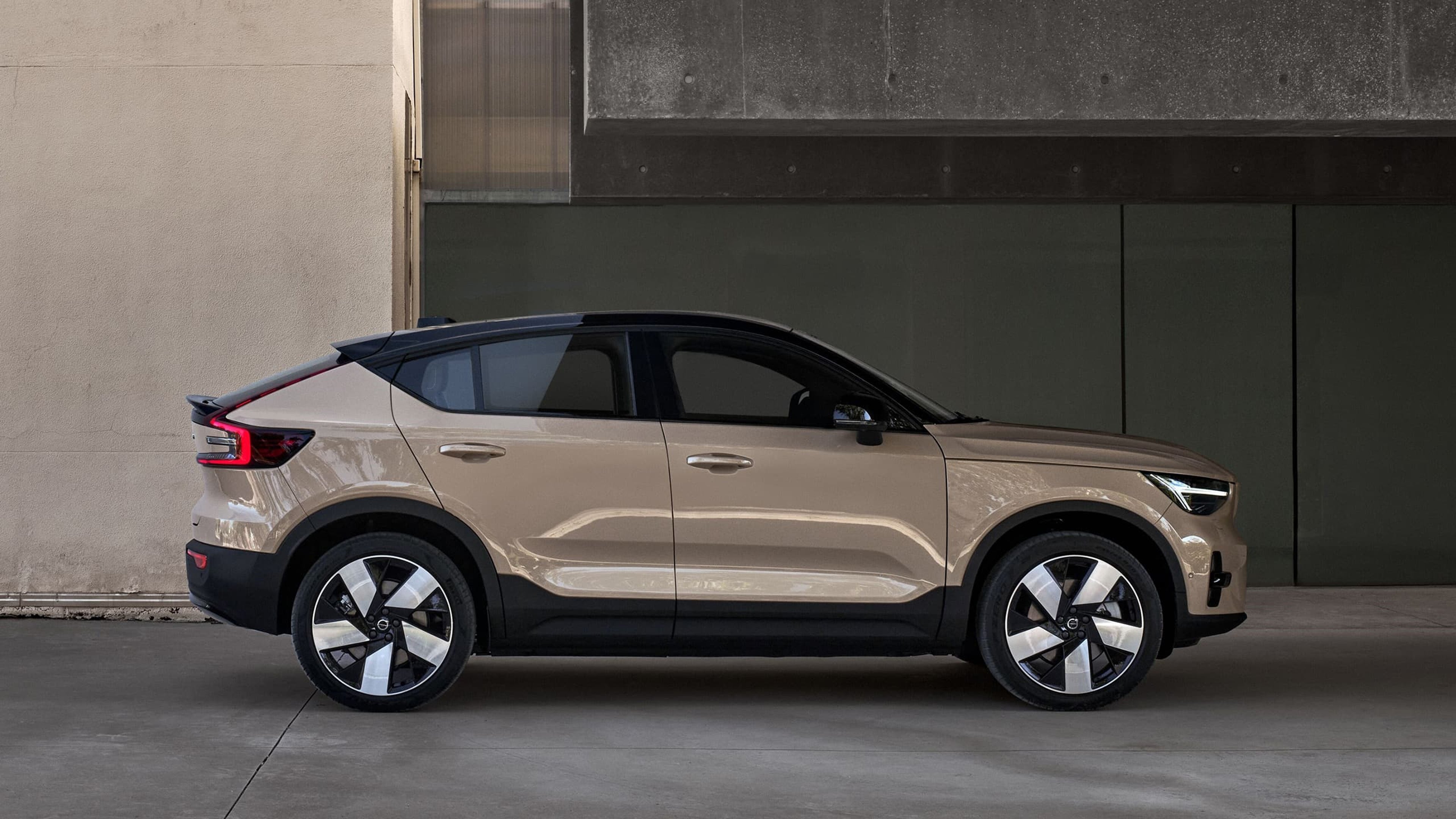 Zijaanzicht van de volledig elektrische Volvo EC40, geparkeerd voor een modern gebouw.