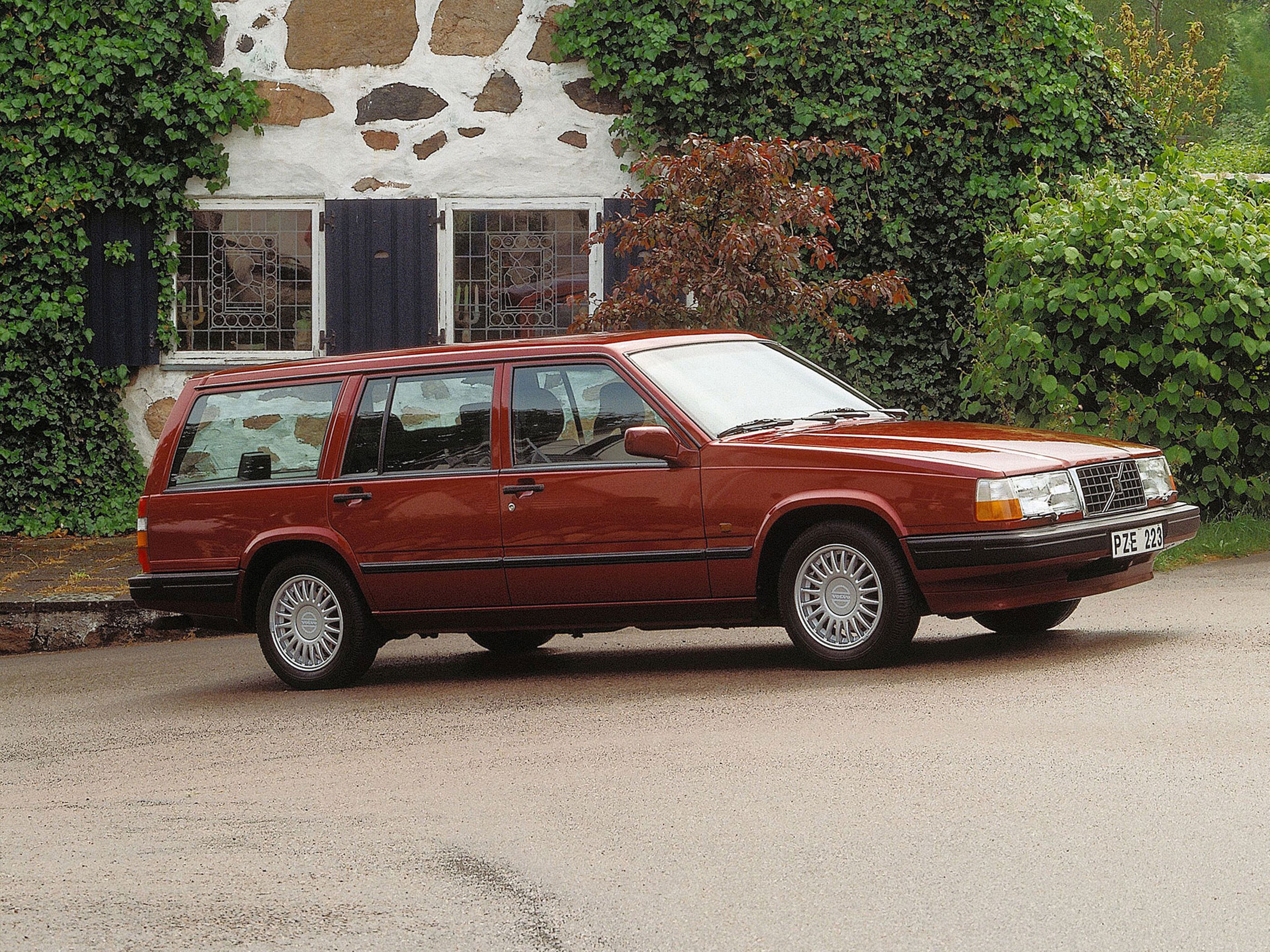 Volvo 940 Break garé près d’une maison de campagne et d’une famille