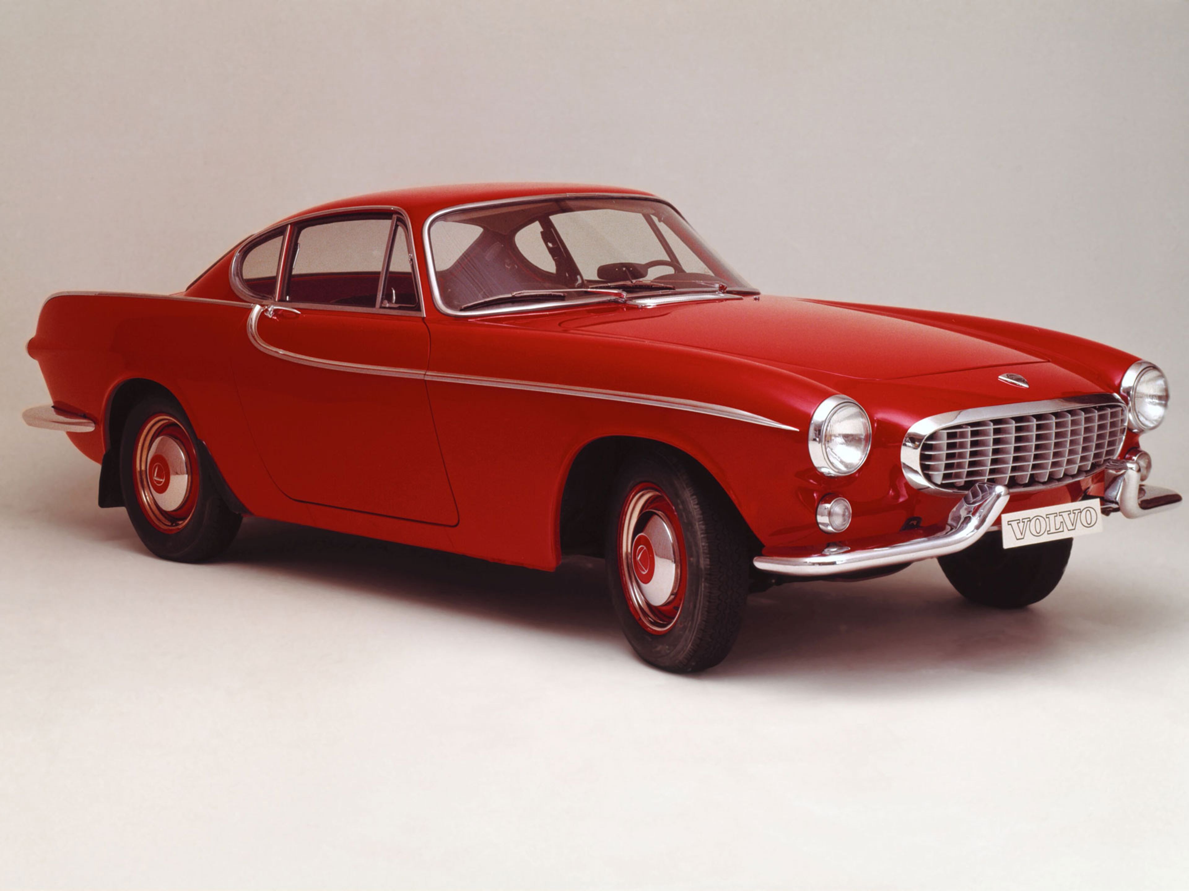 Класично црвено Volvo P1800 Convertible паркирано на плоштад.