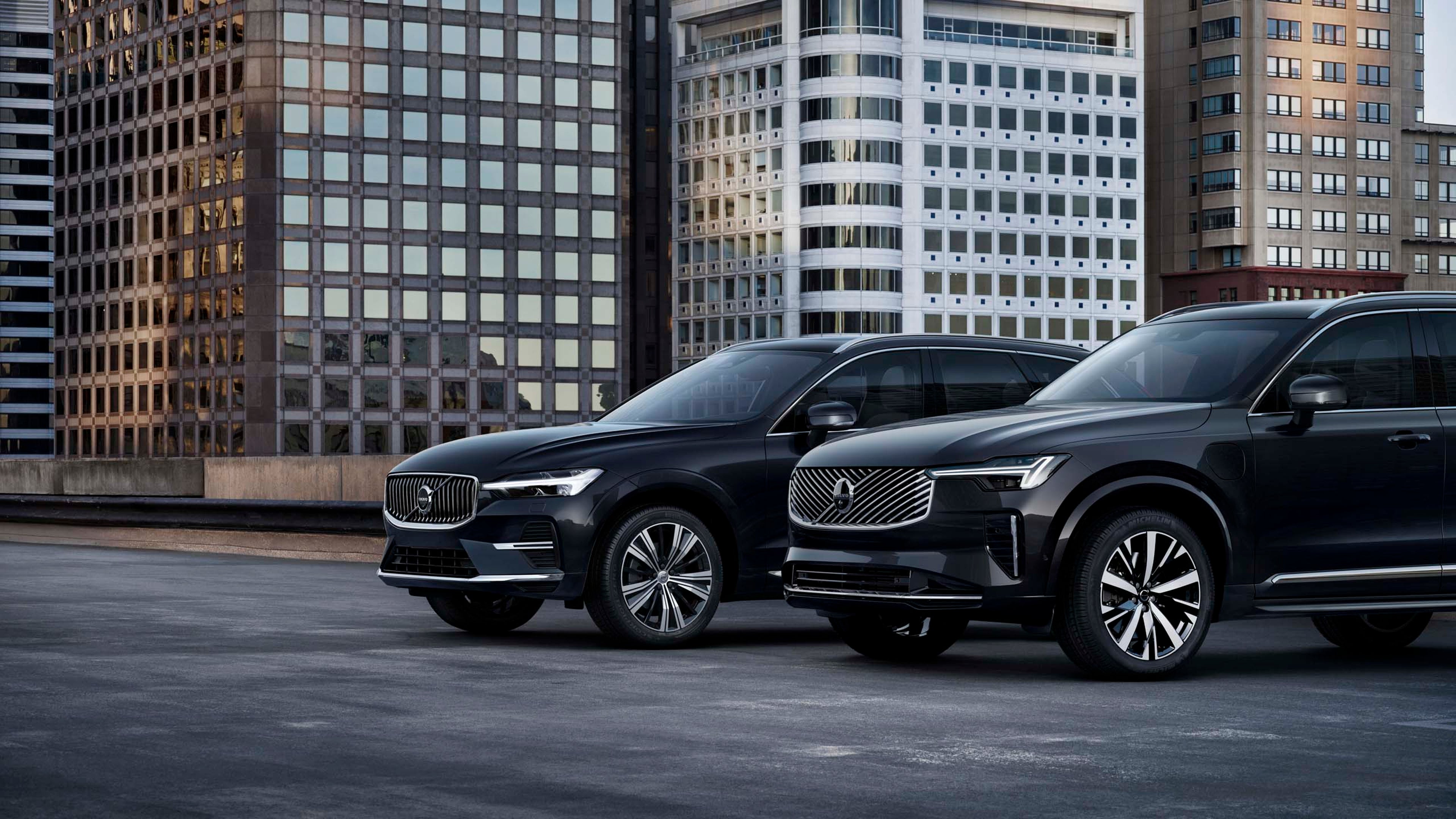Parte frontal de dos vehículos Volvo en una terraza rodeado de edificios.