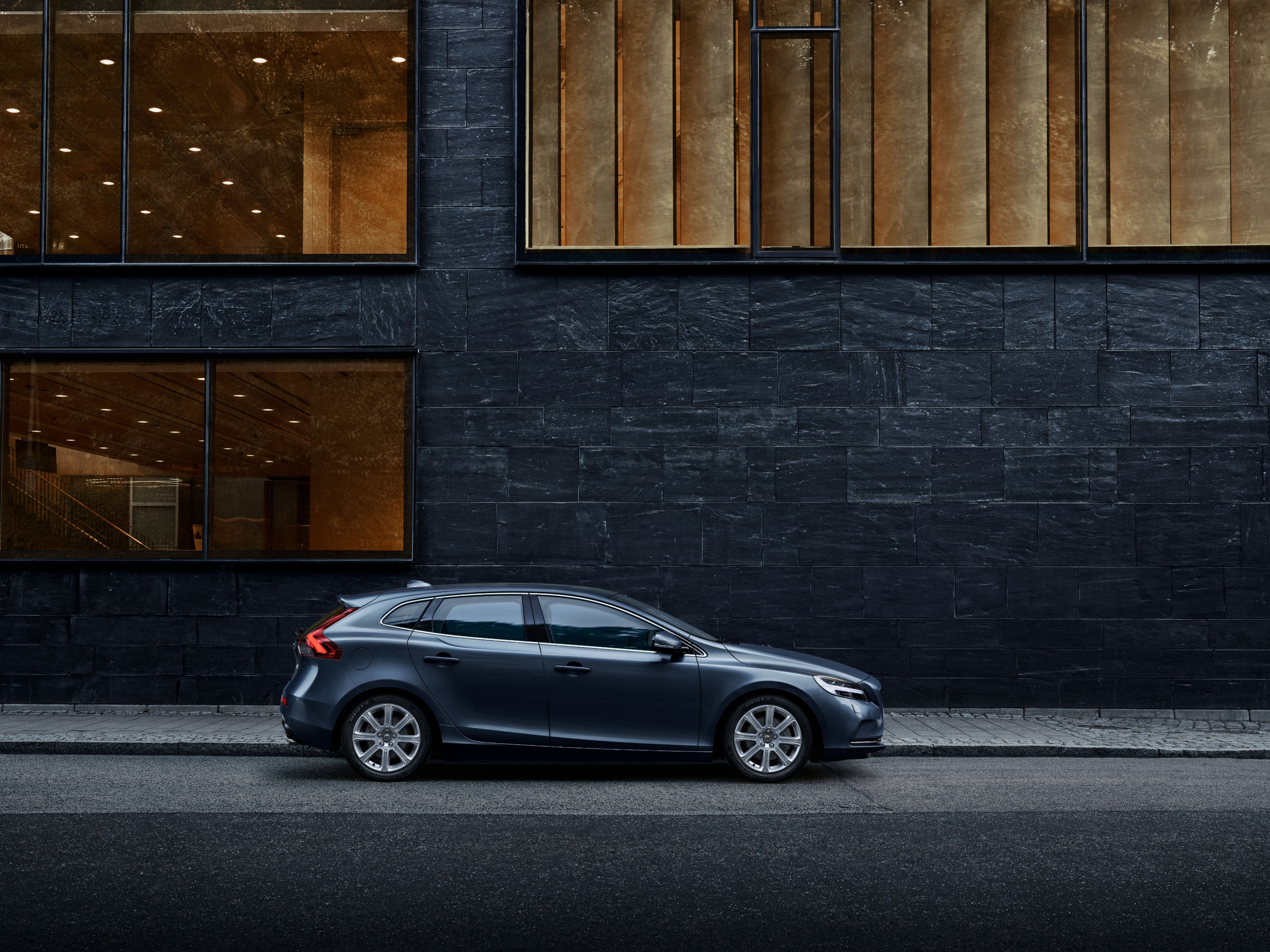 Immagine del lato di una Volvo V40 parcheggiata accanto a una casa.