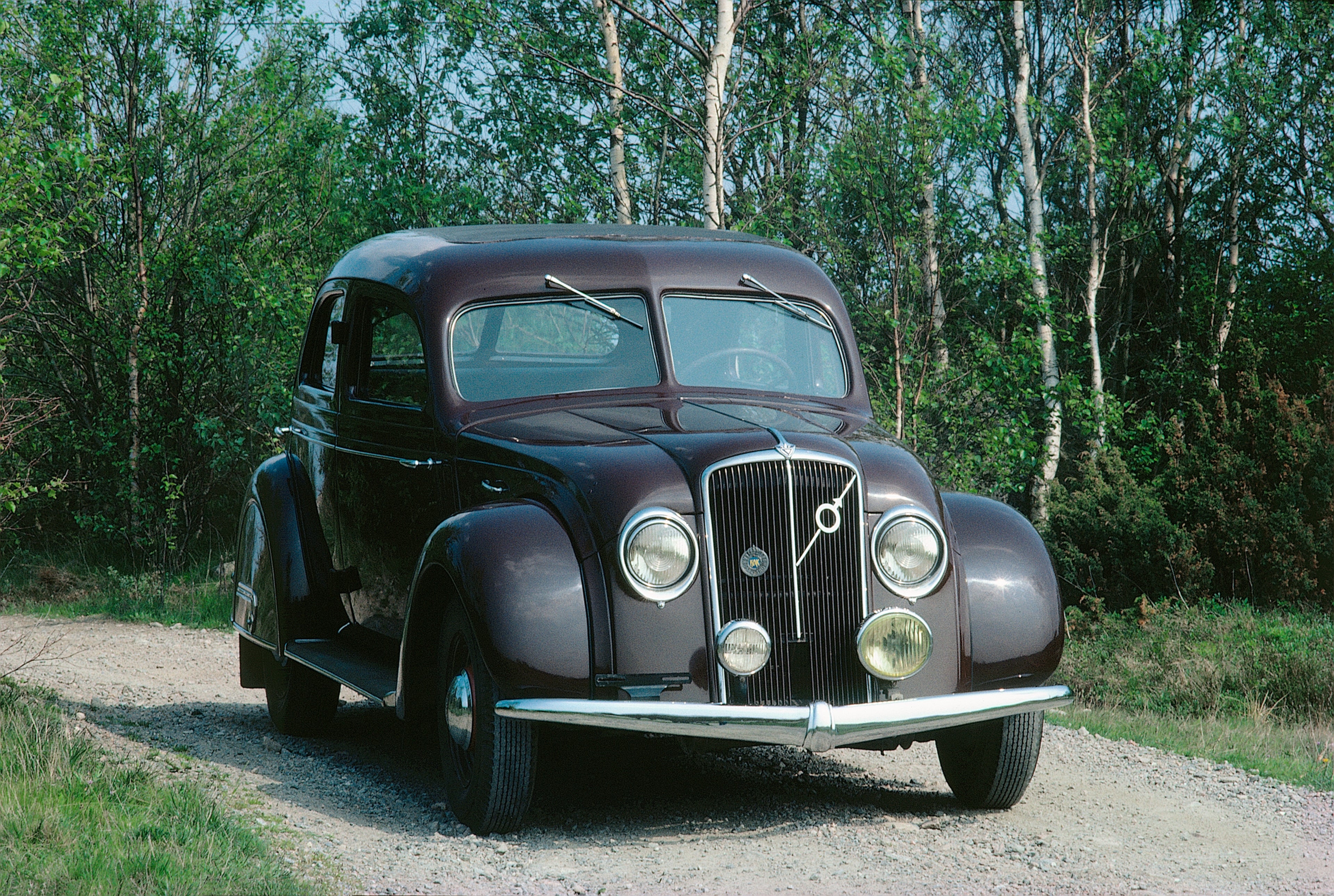 Volvo PV36 Carioca garée dans un pré, avec deux personnes en train de pique-niquer devant la voiture.