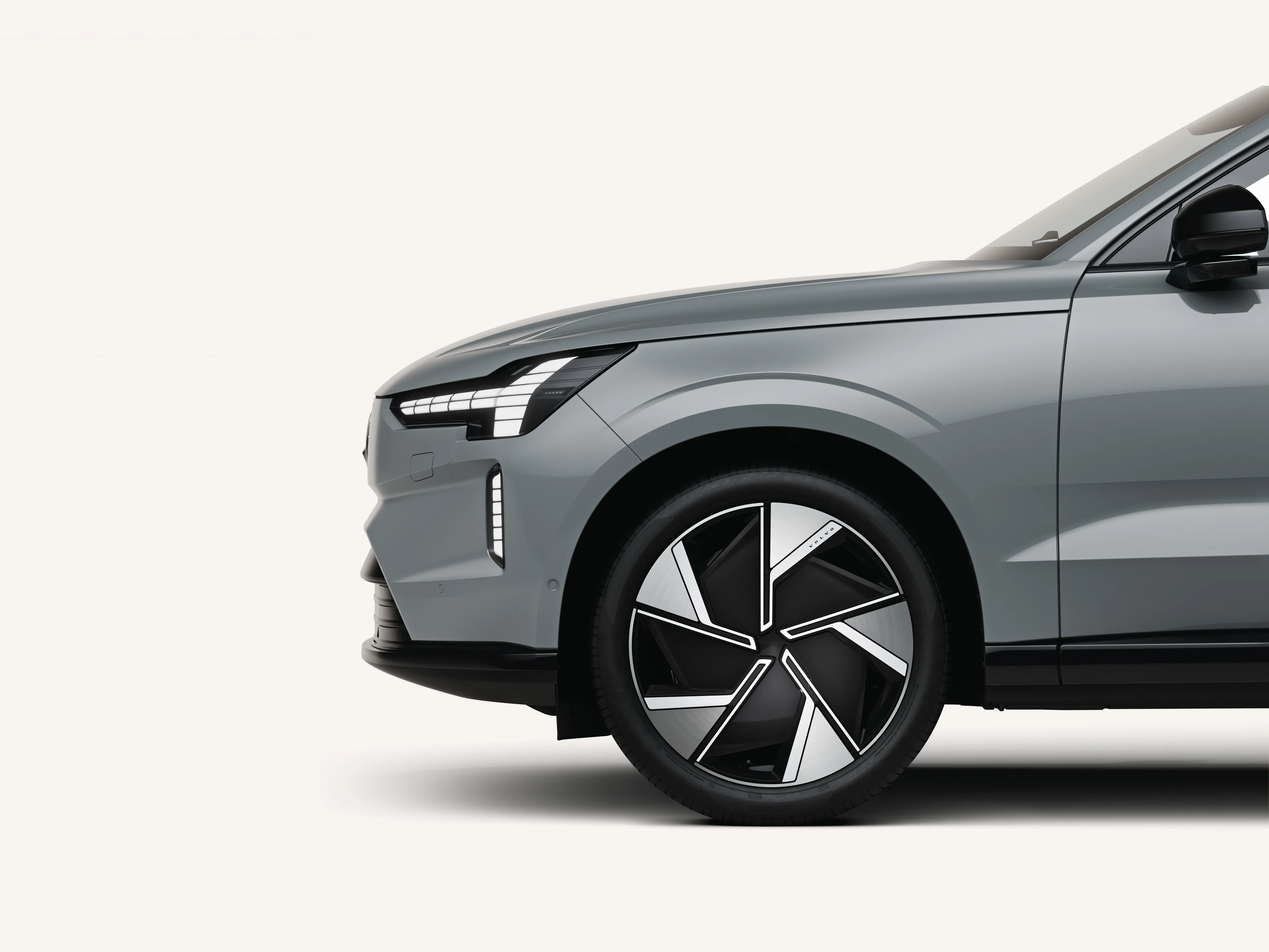 Främre halvan av Volvo EX90 i vit studiomiljö.