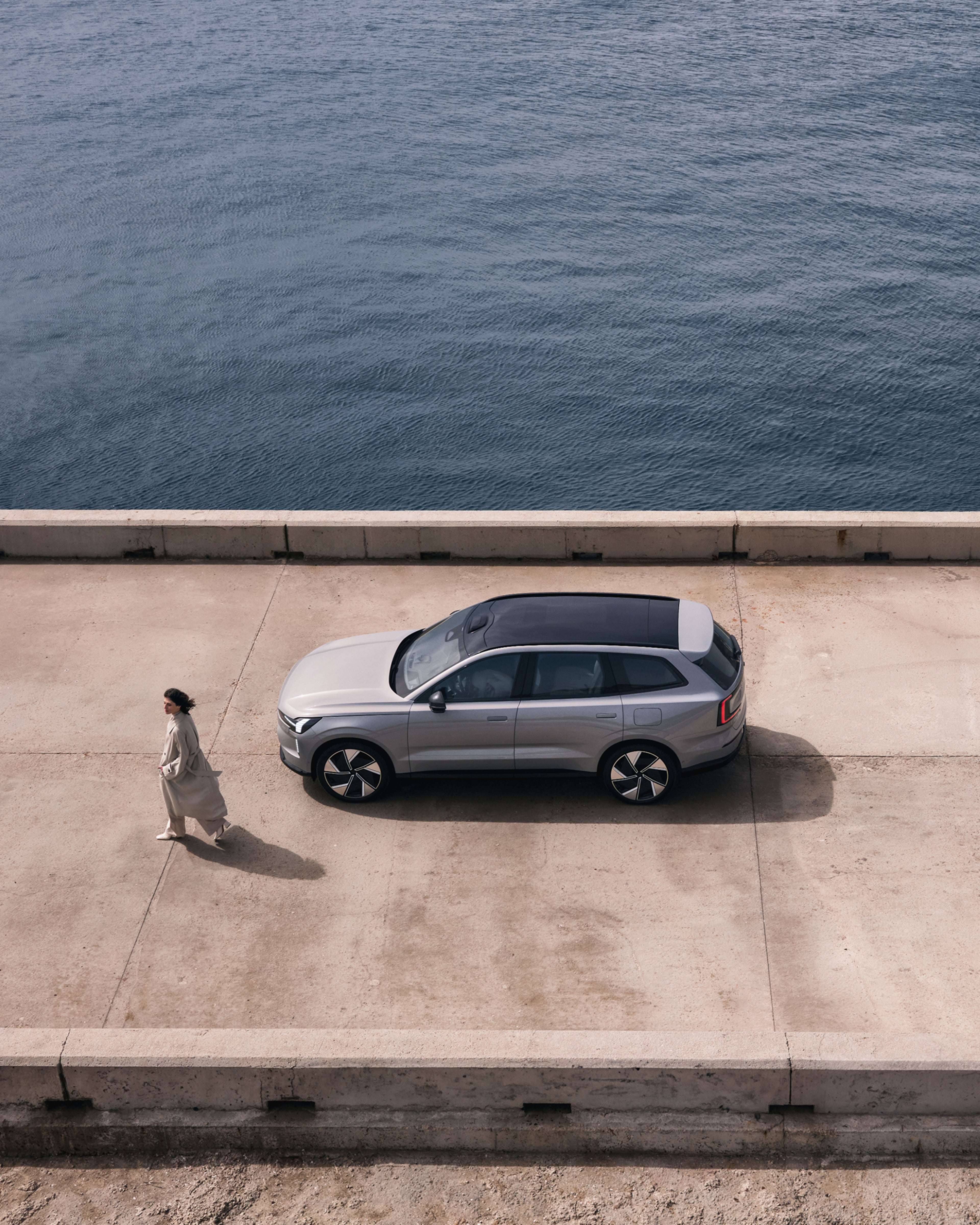 Vue panoramique montrant une femme sortant d’une voiture EX90 garée, vue d’en haut.
