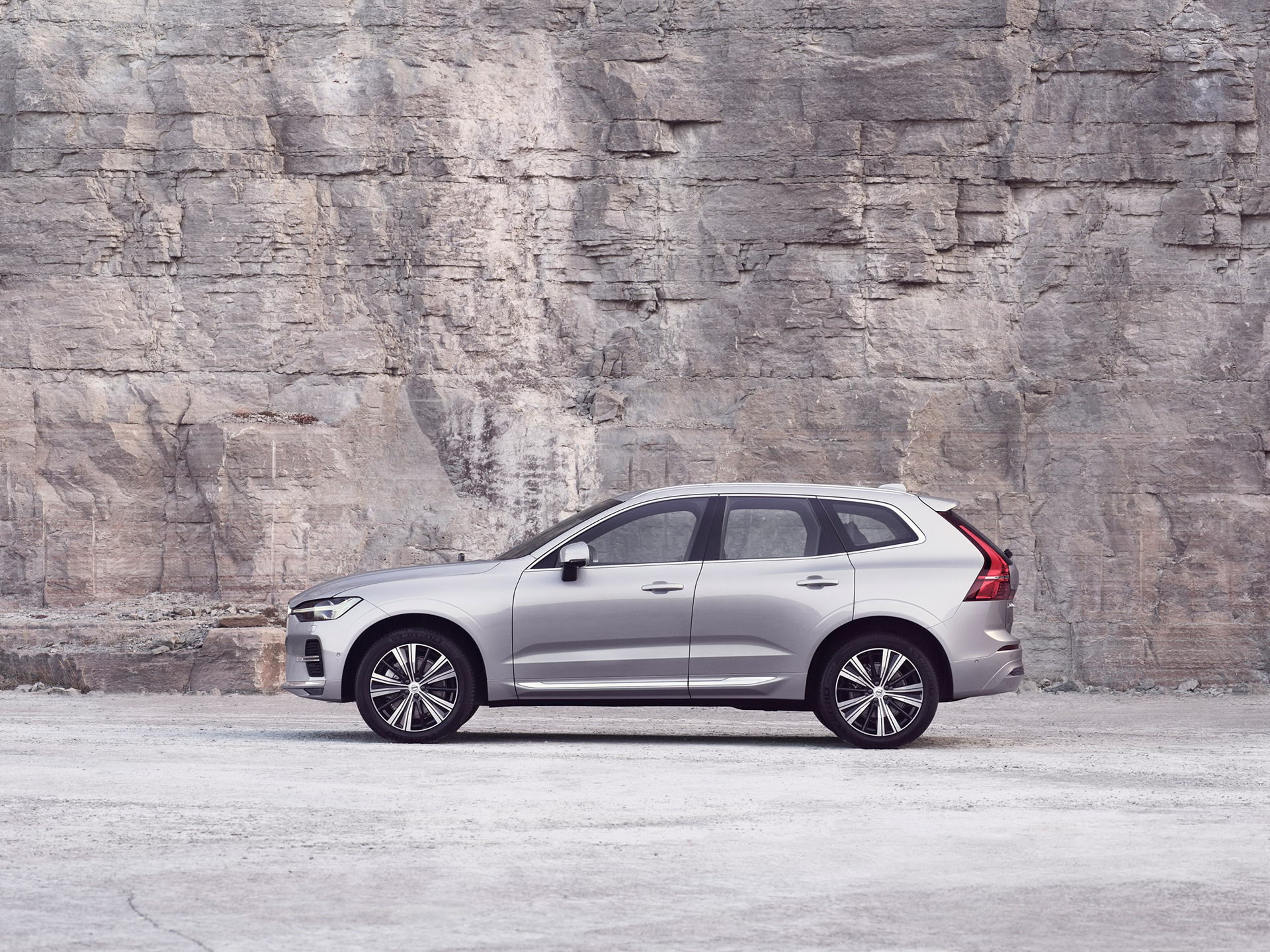 Un Volvo XC60 plateado parado frente a una pared de roca.