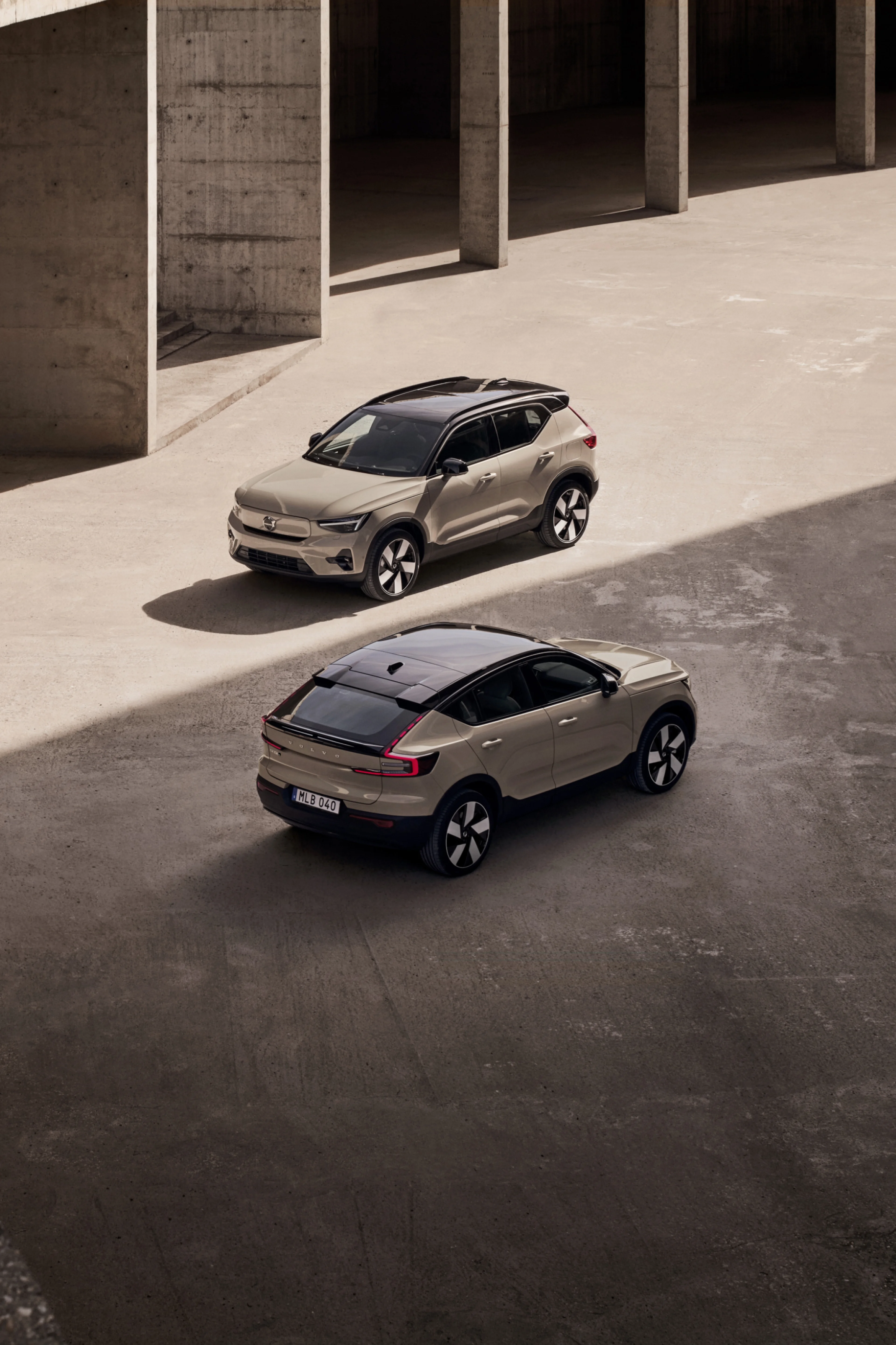 Plne elektrické vozidlá Volvo EC40 a EX40 zaparkované vedľa seba v pôsobivom vonkajšom prostredí.