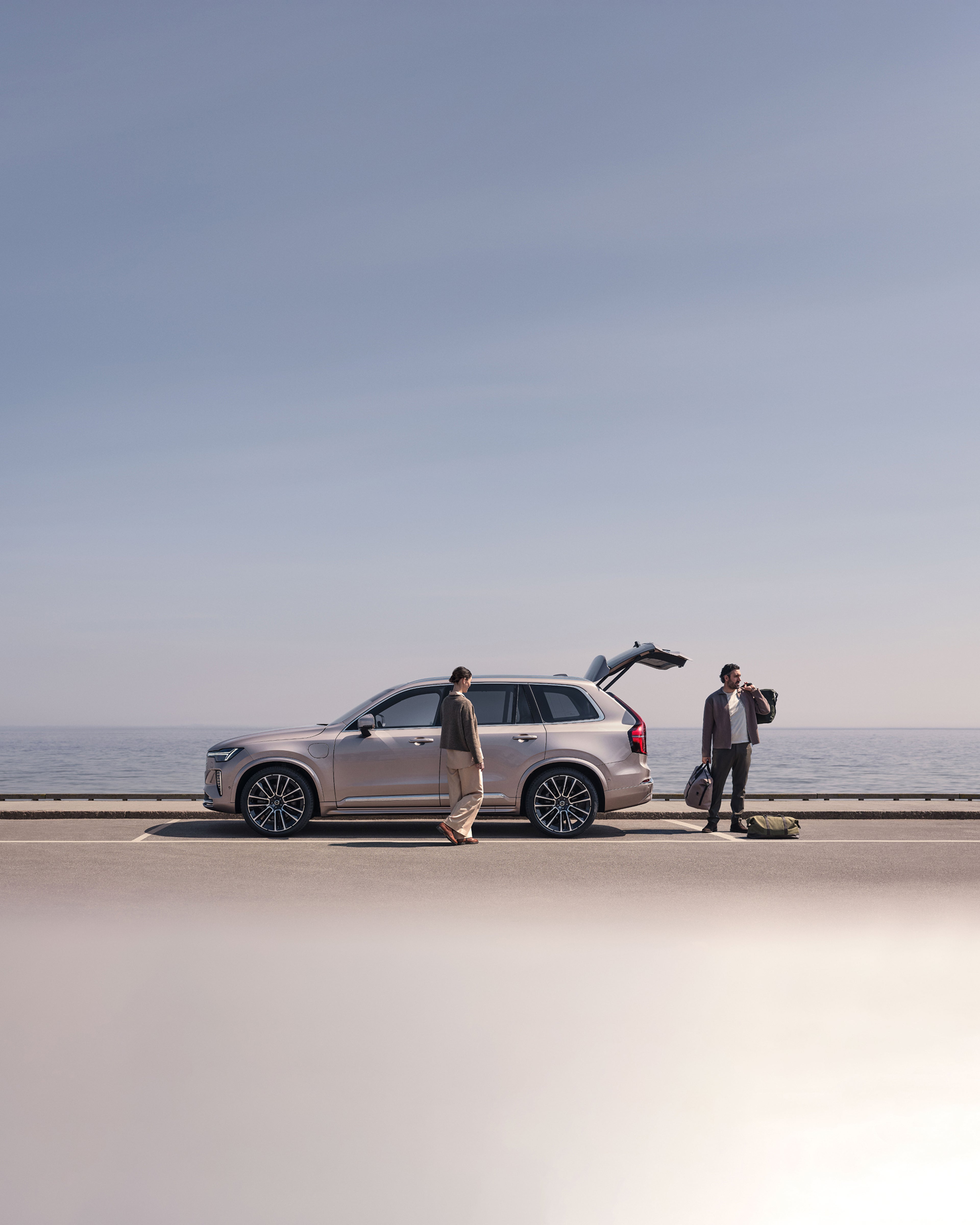 Eine Frau und ein Mann packen ihren Volvo XC90 neben dem Wasser