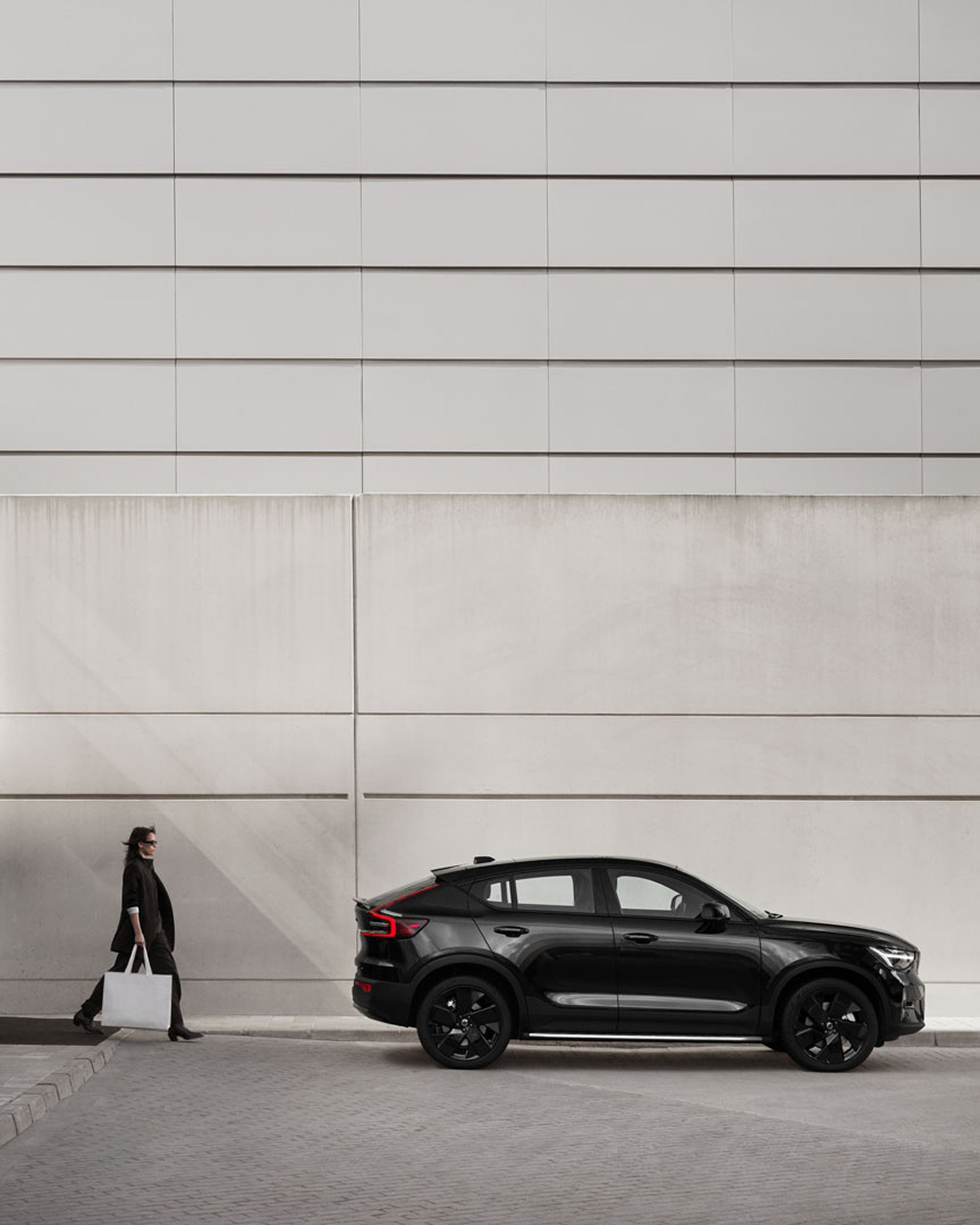 A woman walking towards the side facing Volvo EC40.