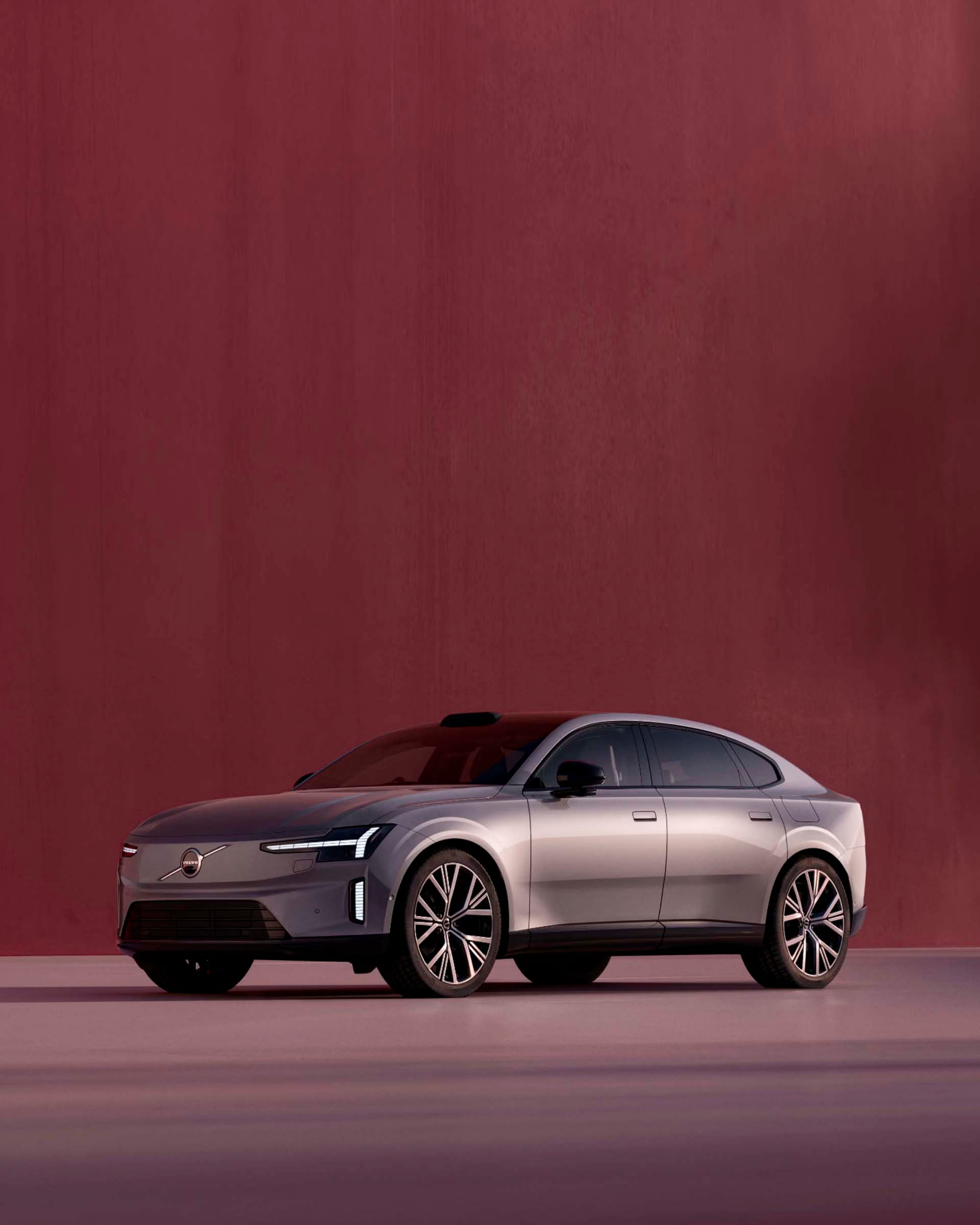 Vista lateral de un Volvo ES90 eléctrico con un fondo rojo burdeos
