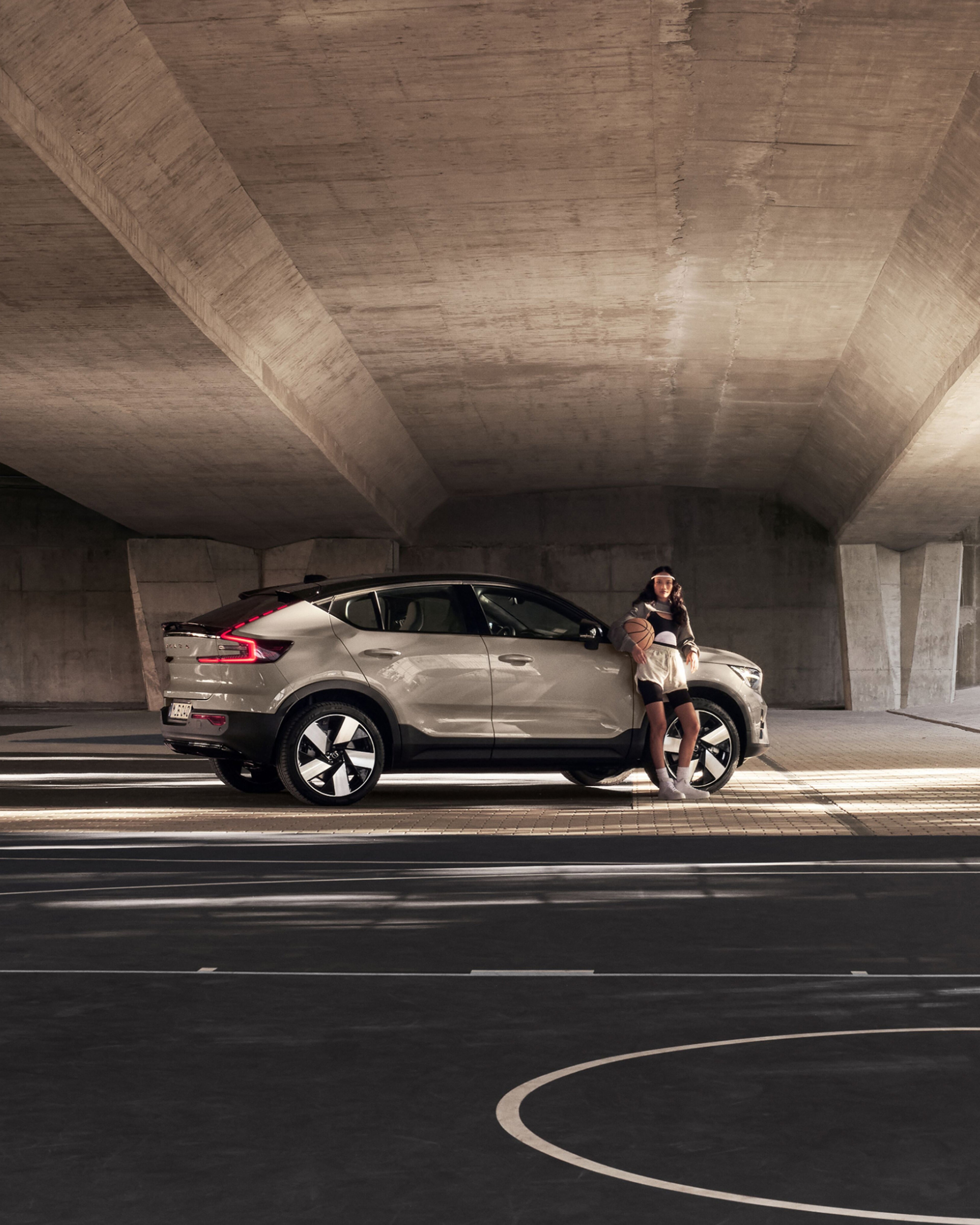 Una mujer de pie junto al Volvo EC40 enfocándose en el costado