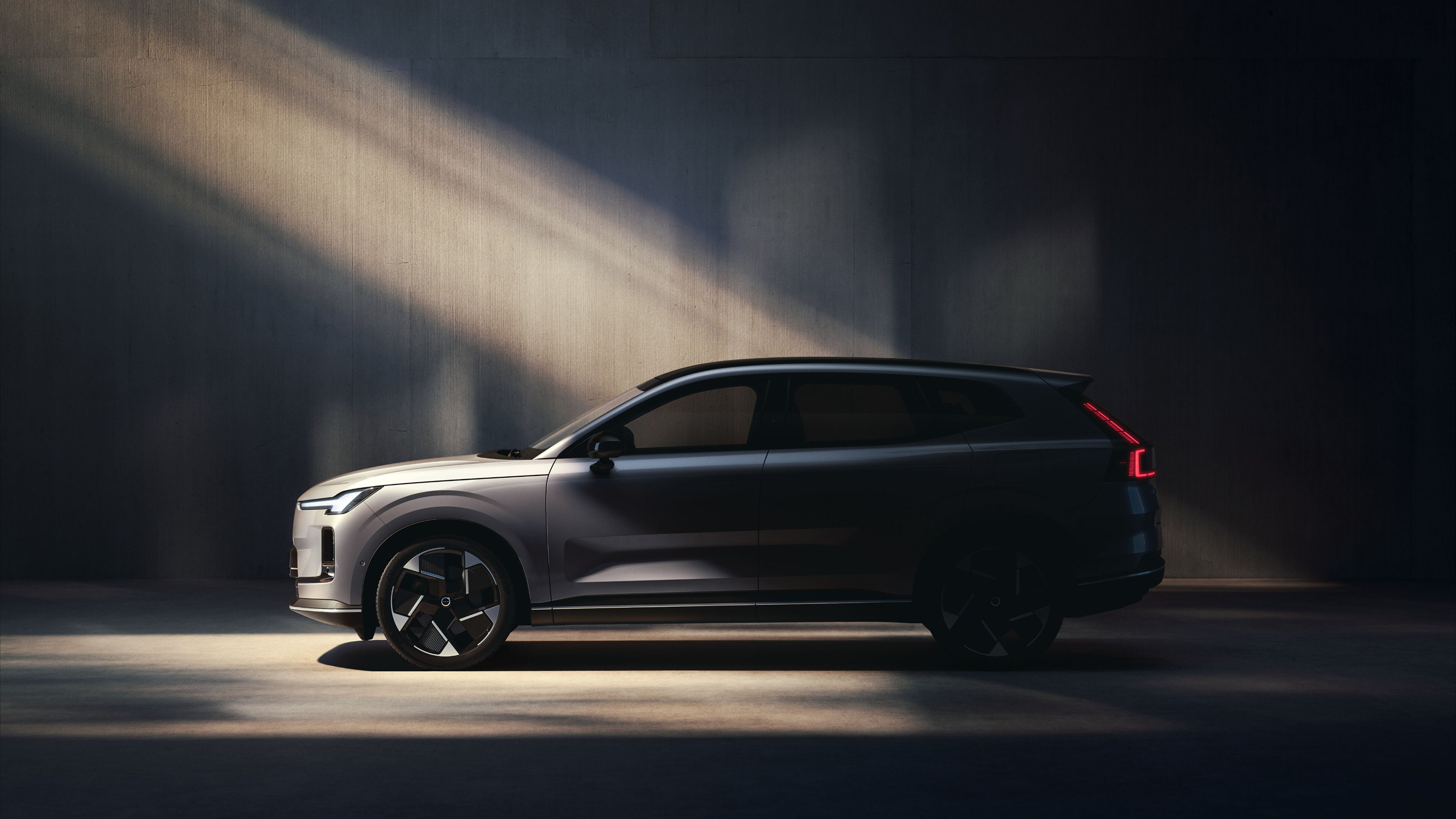 Left side view of the Volvo XC70 with its headlights on.