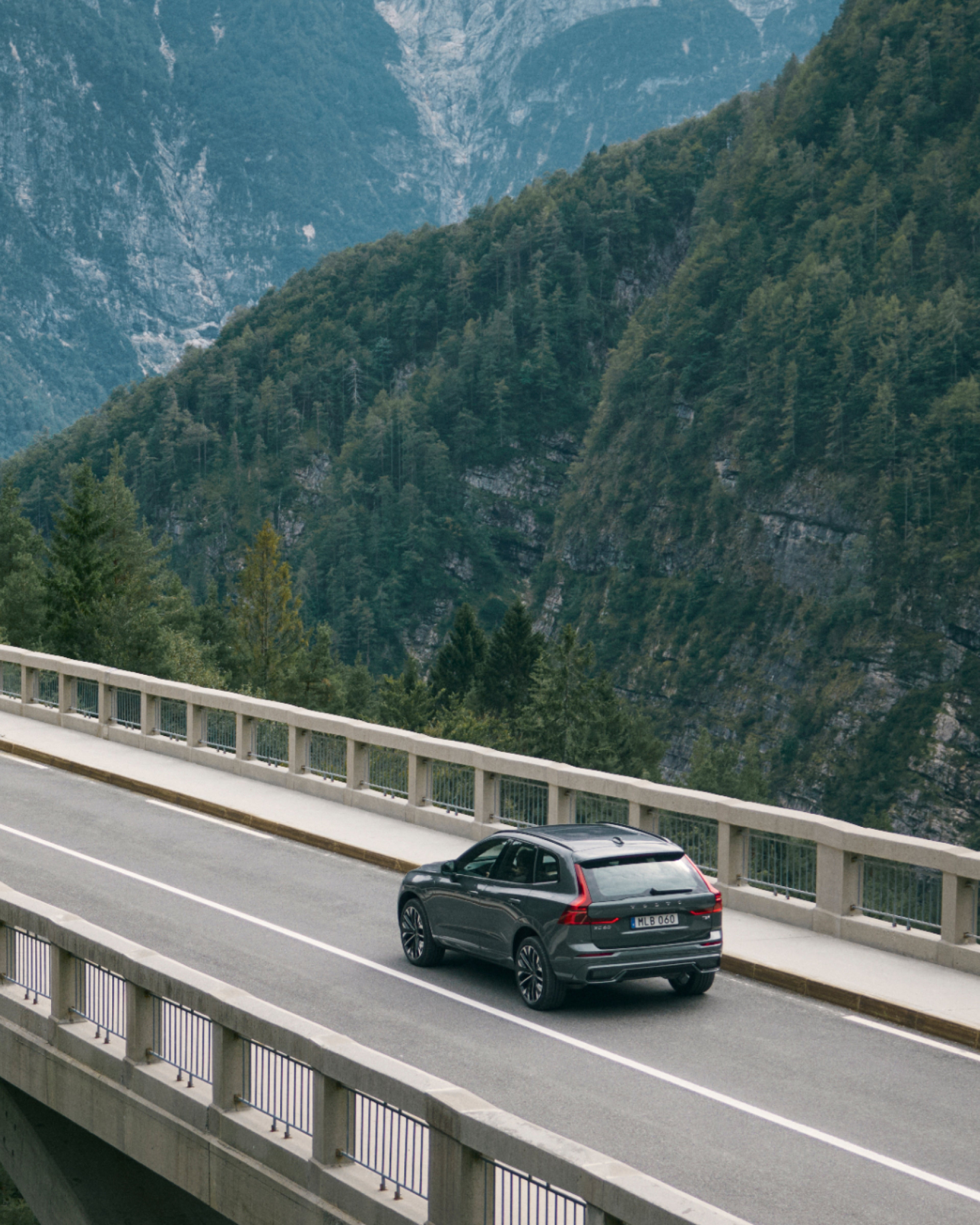 Un Volvo XC60 pasa por un puente contra un paisaje montañoso.