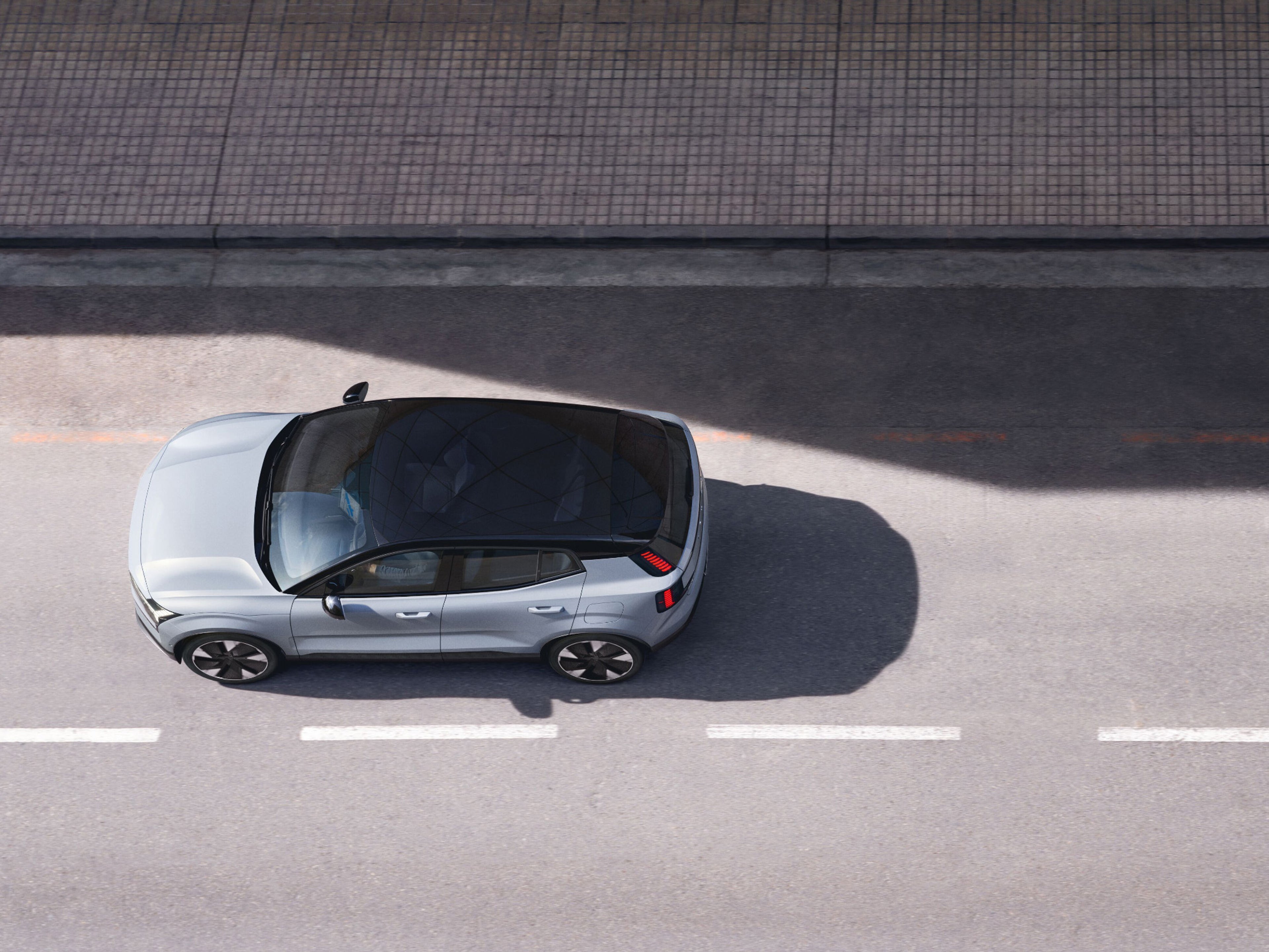 A silver Volvo XC60 Recharge, charging in a white surrounding.