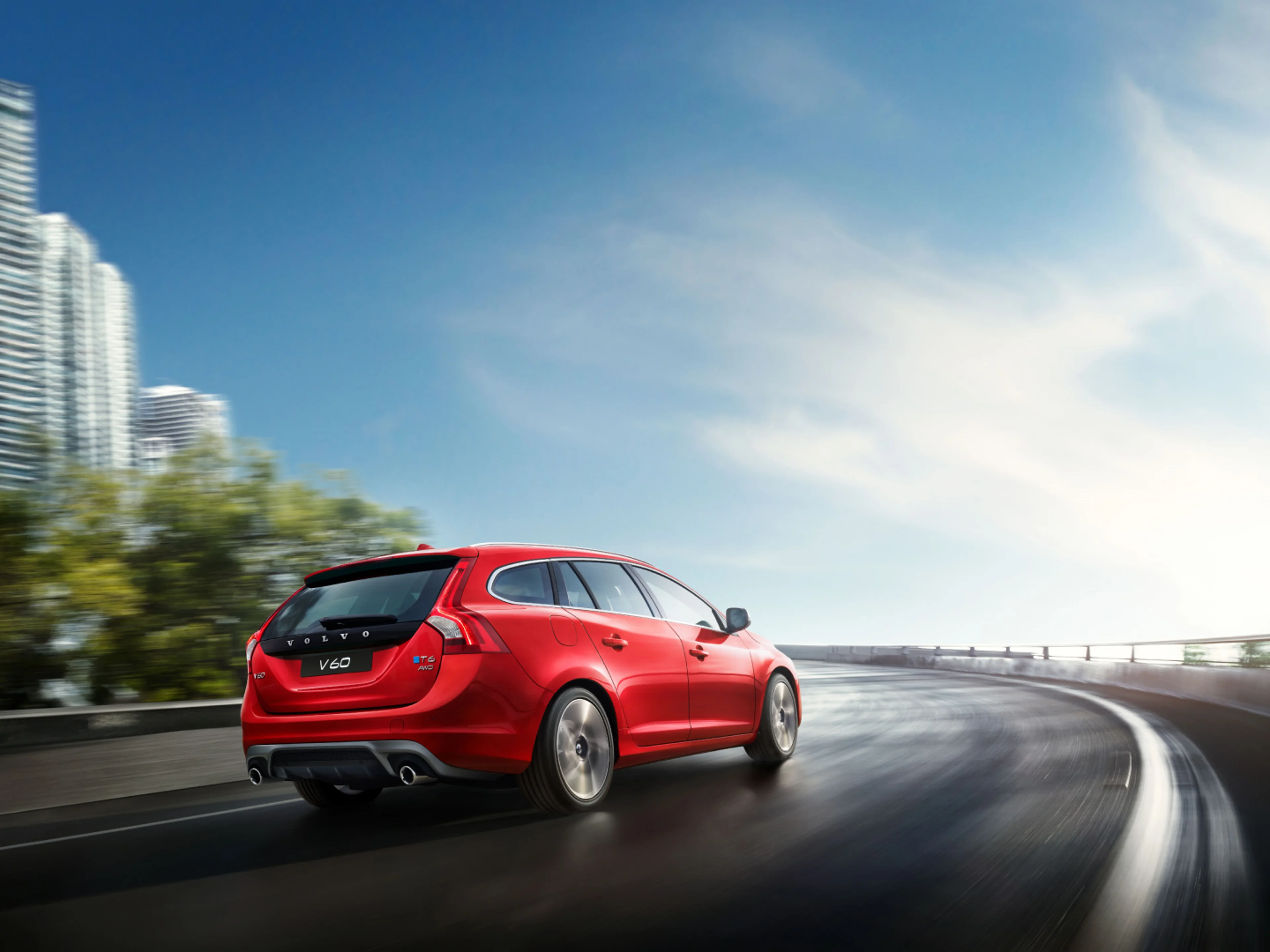 Image d’un Volvo V60 bleu roulant sur une route bordée d’arbres.