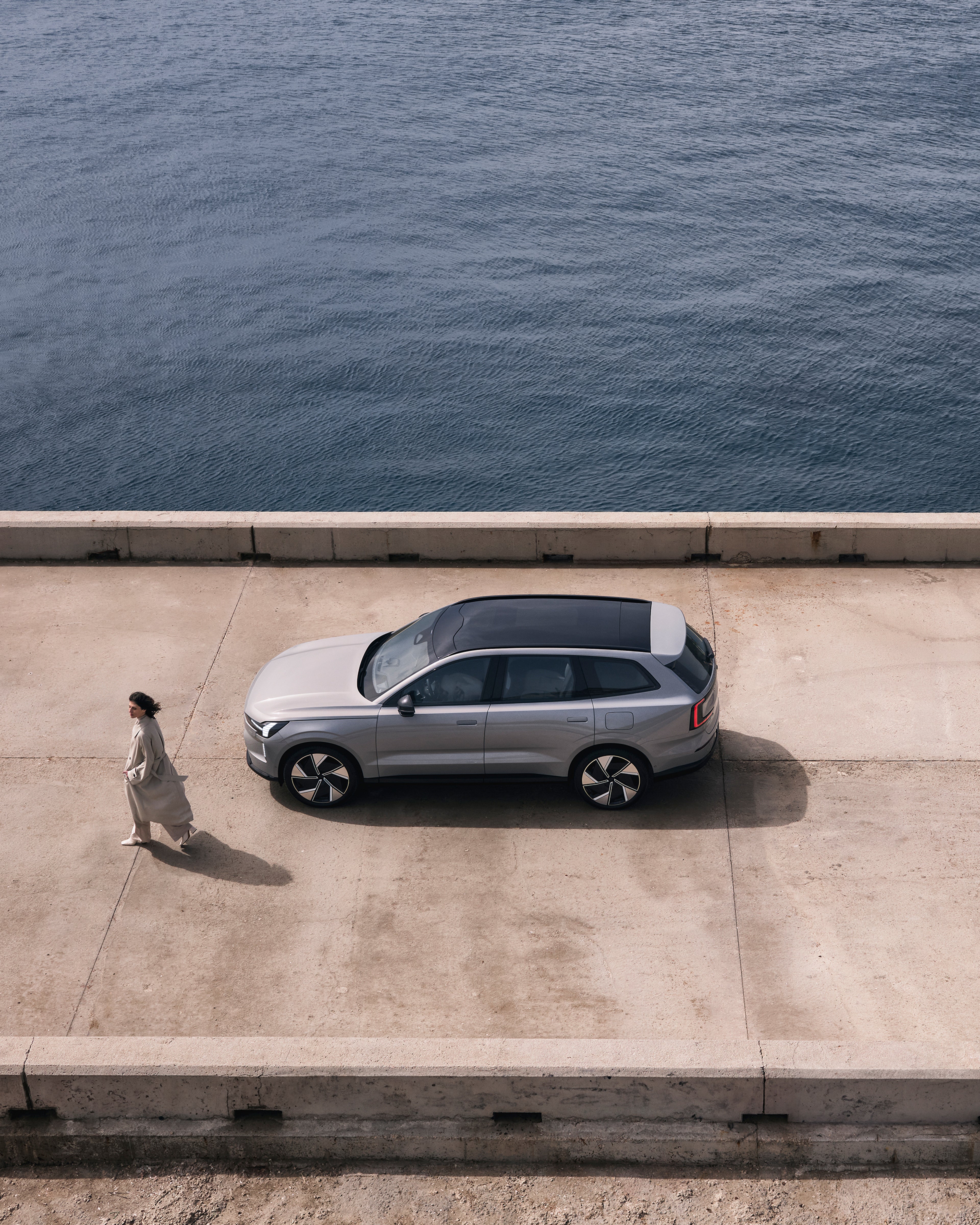 Eine Panoramaansicht mit einer Frau, die aus einem im EX90 geparkten Auto von oben kommt.