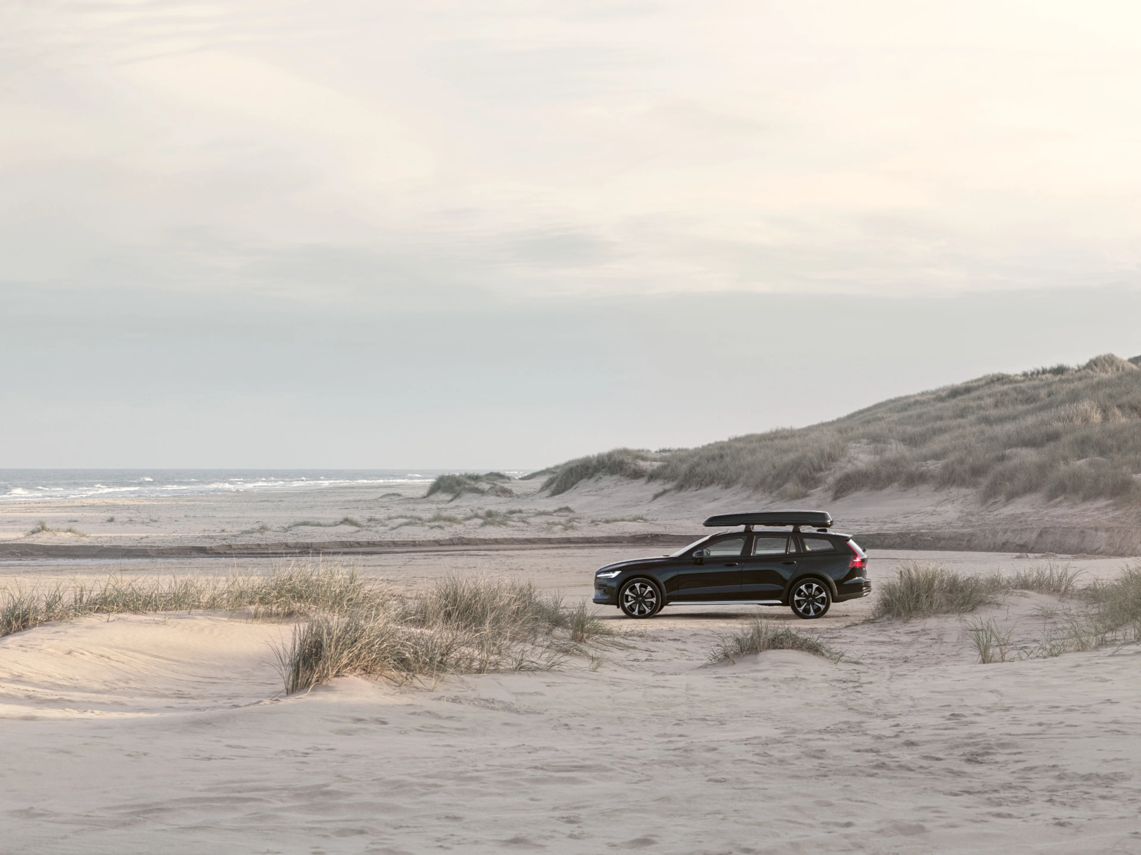 Image d’un Volvo V60 garé au milieu de dunes de sable.