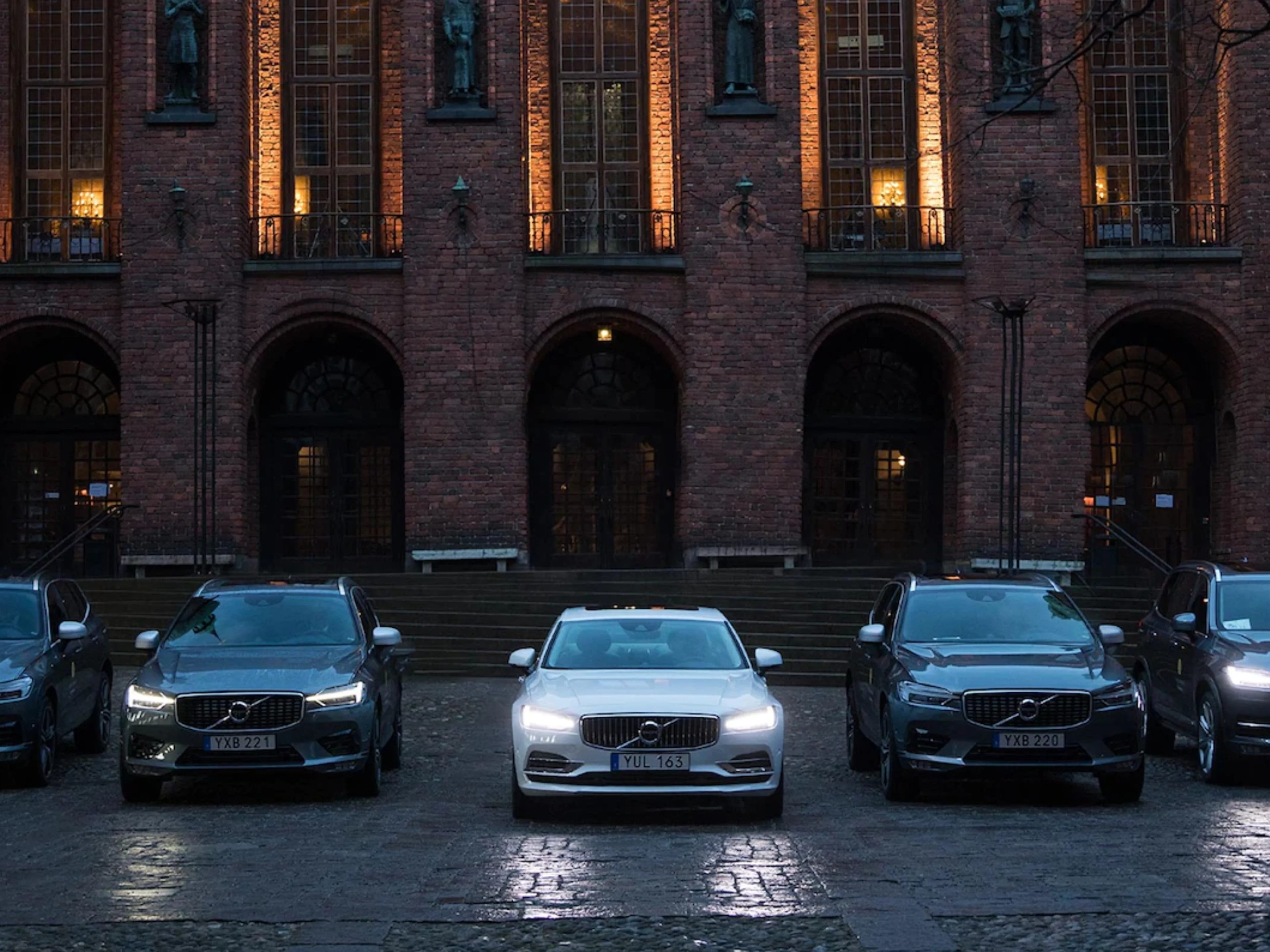 Plusieurs véhicules Volvo devant un bâtiment la nuit