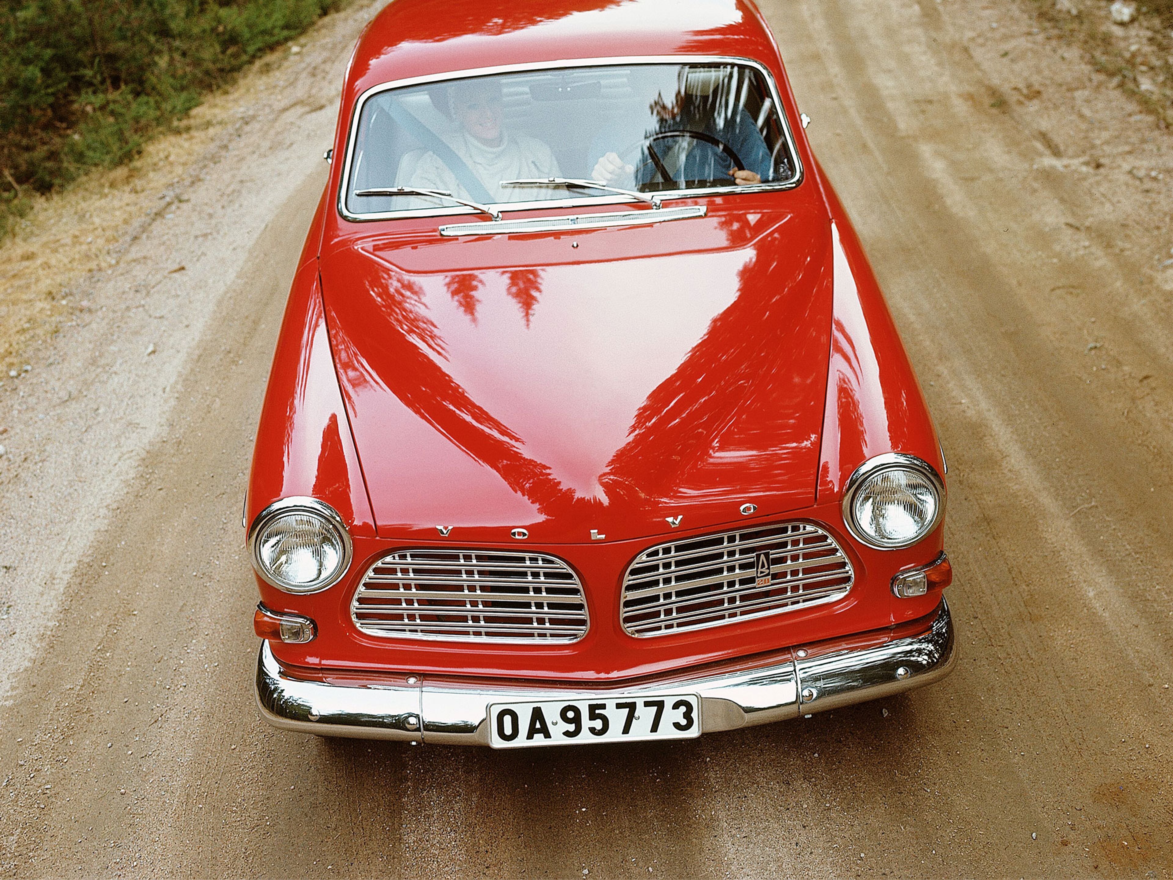 Volvo P130 rouge vu de face et circulant sur un chemin de terre