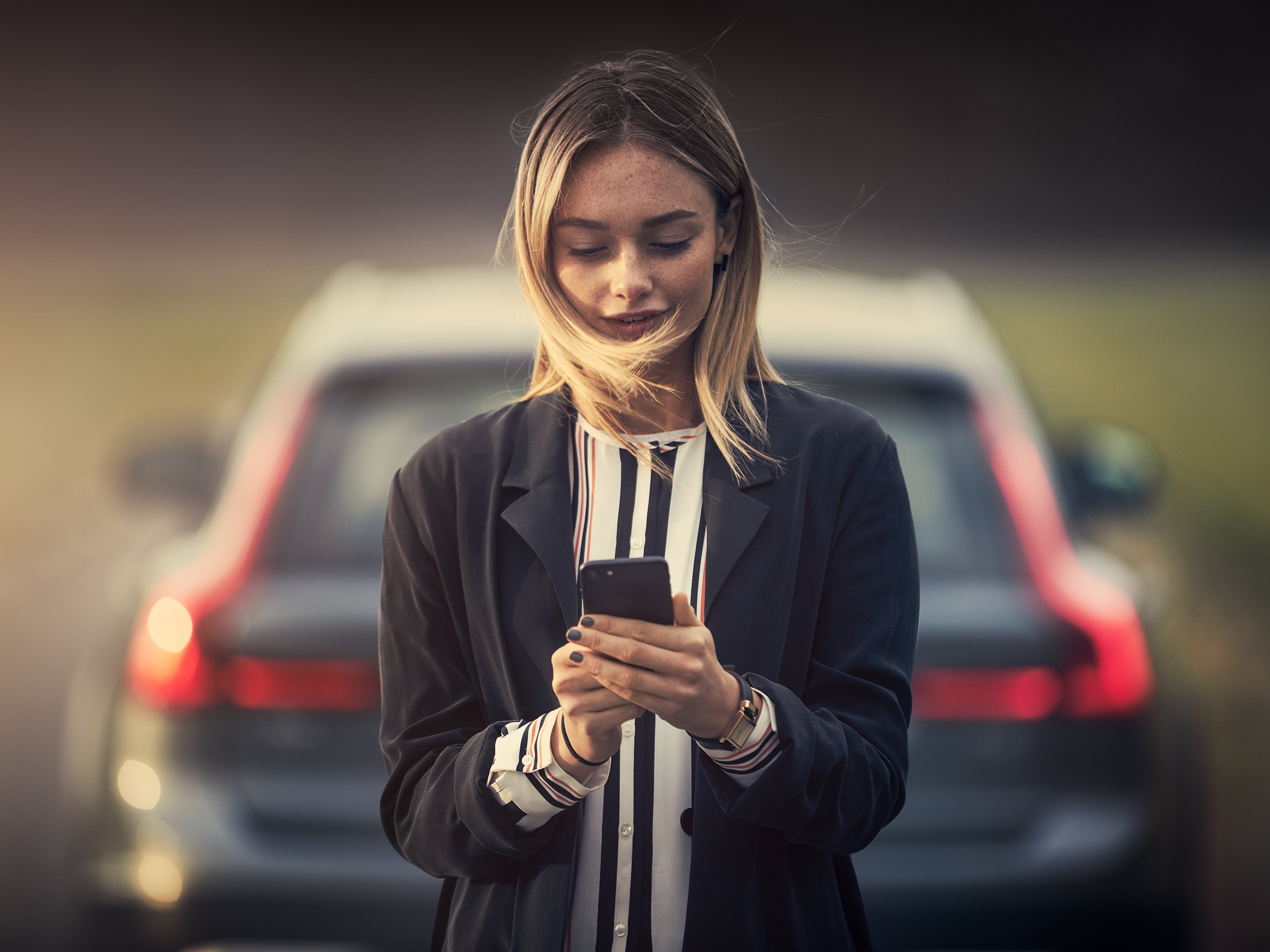 Volvo Cars Applikációt használó hölgy egy Volvo modell mögött