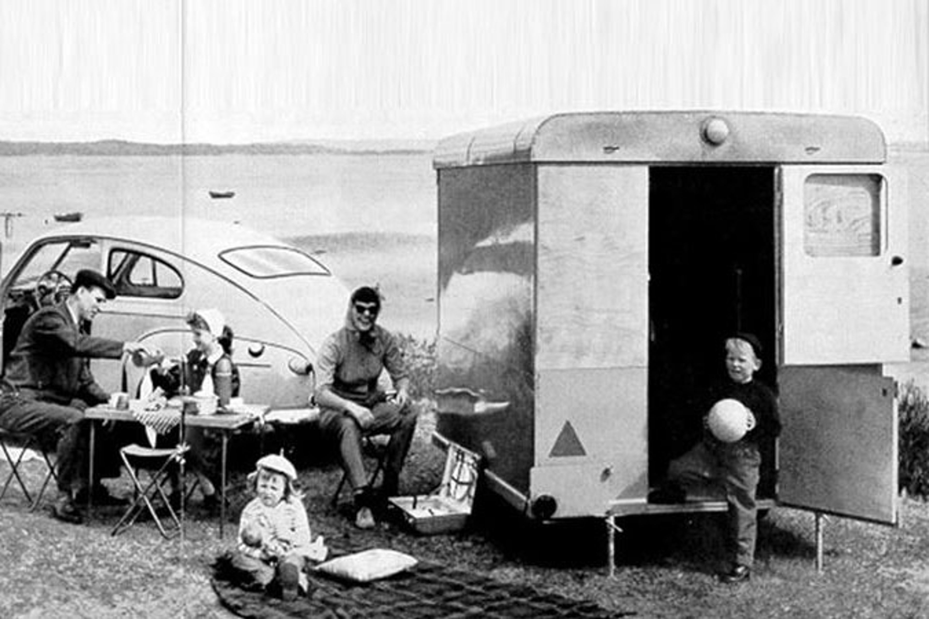Una foto en blanco y negro que muestra a una familia y su caravana/remolque Volvo.