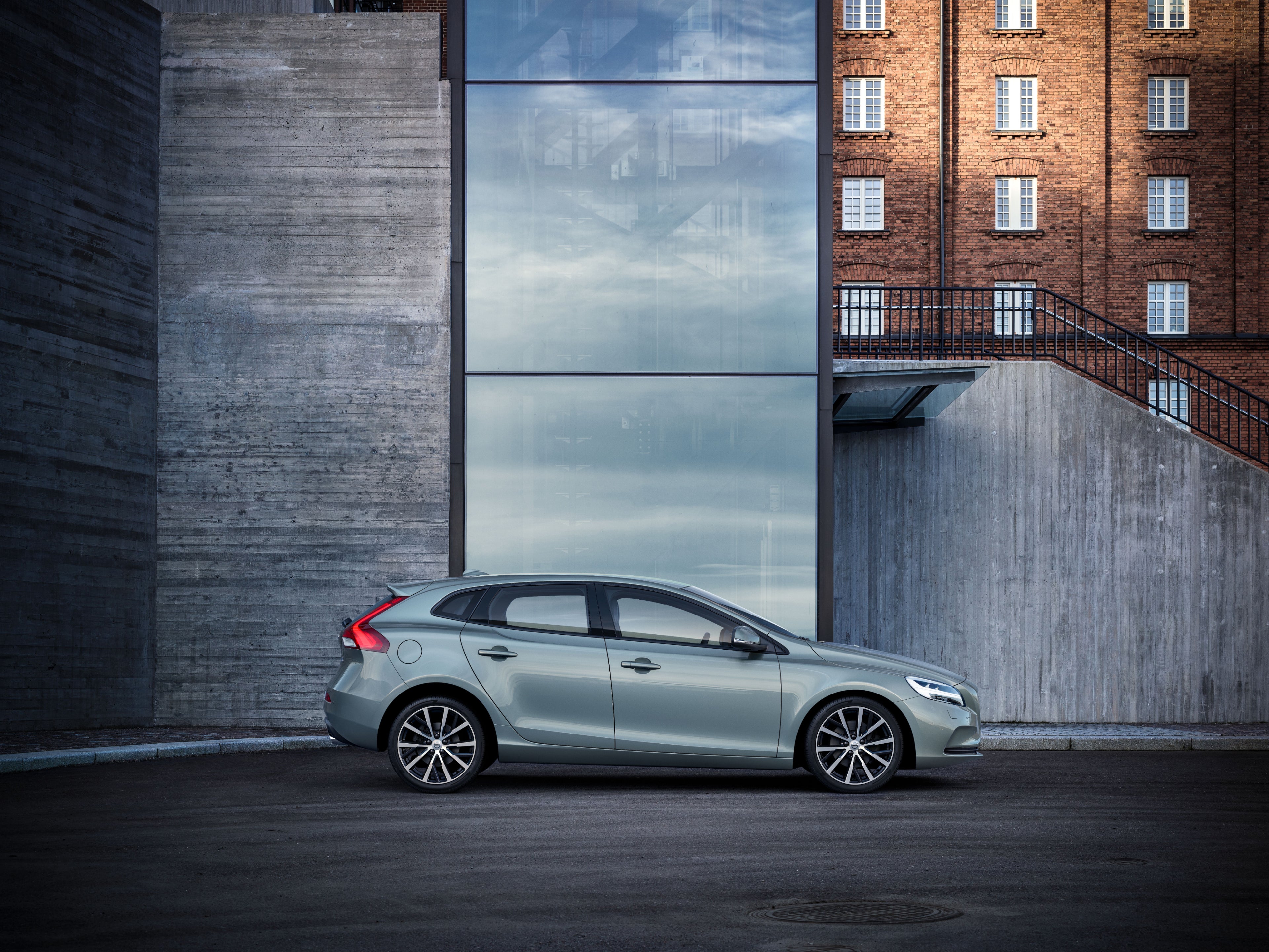 Imagen del lateral de un Volvo V40 estacionado junto a un edificio de hormigón y cristal.