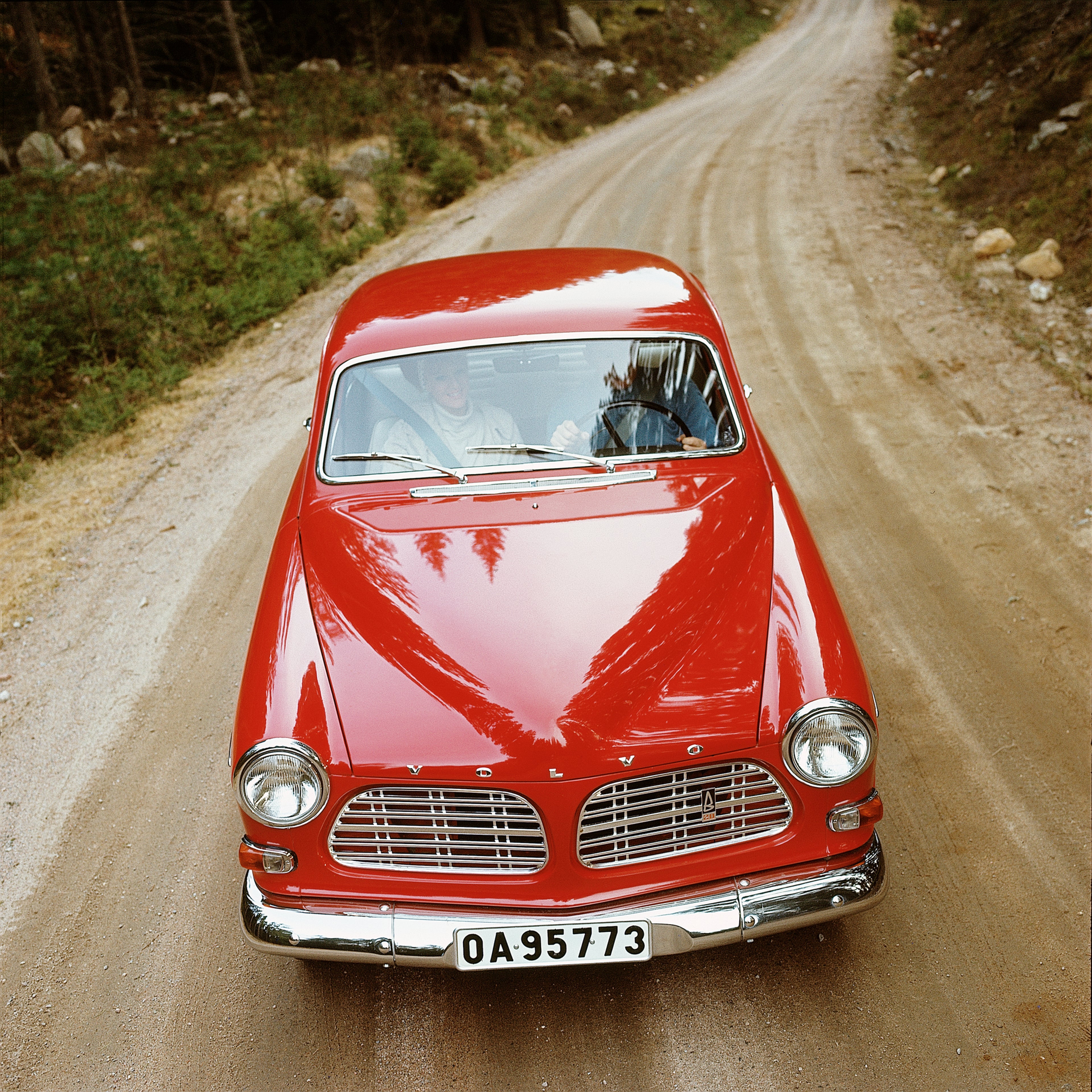 Volvo P130 Amazon rouge garée dans un paysage verdoyant et vallonné.