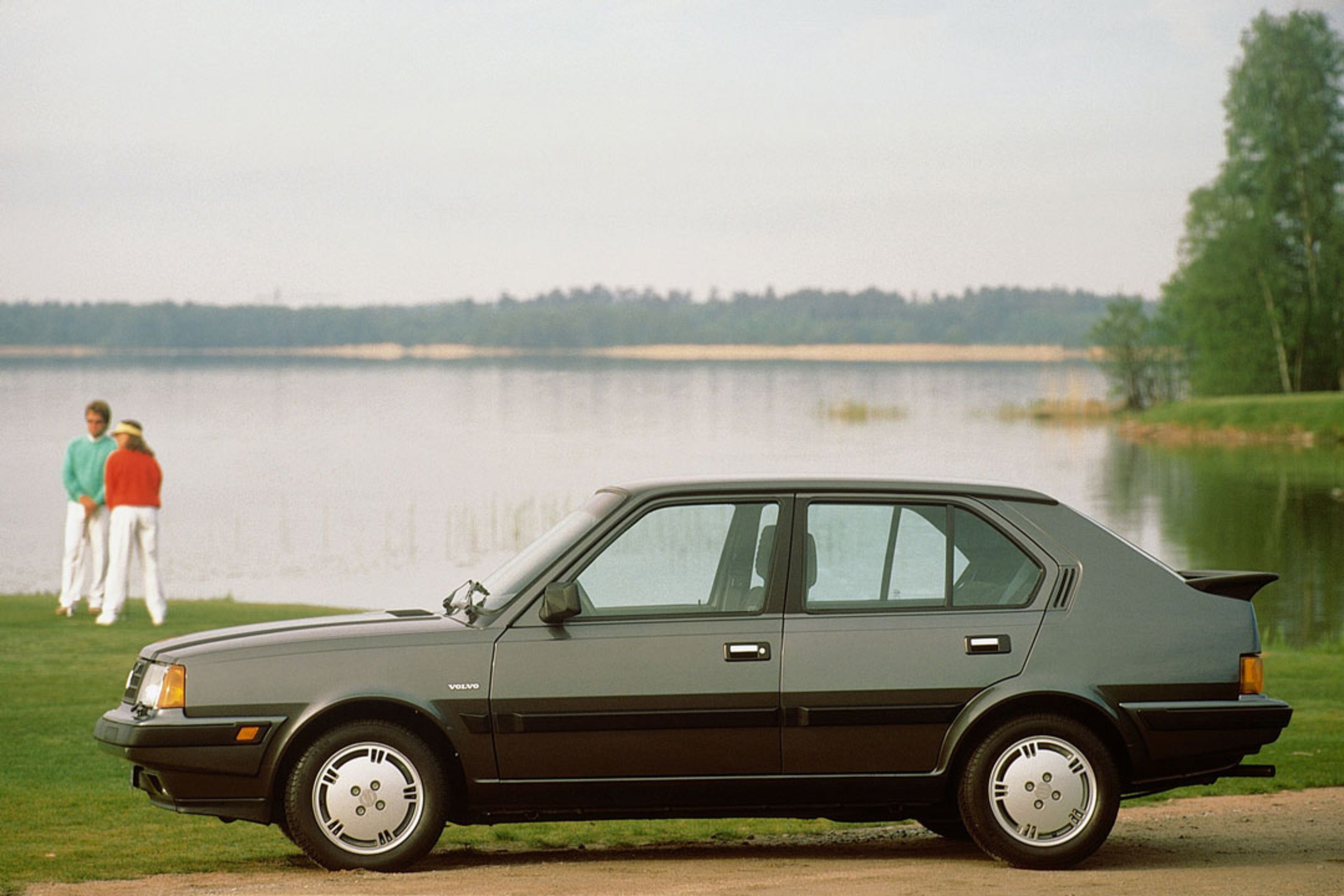 Un sedán Volvo 360 de 5 puertas aparcado cerca de un campo de golf.