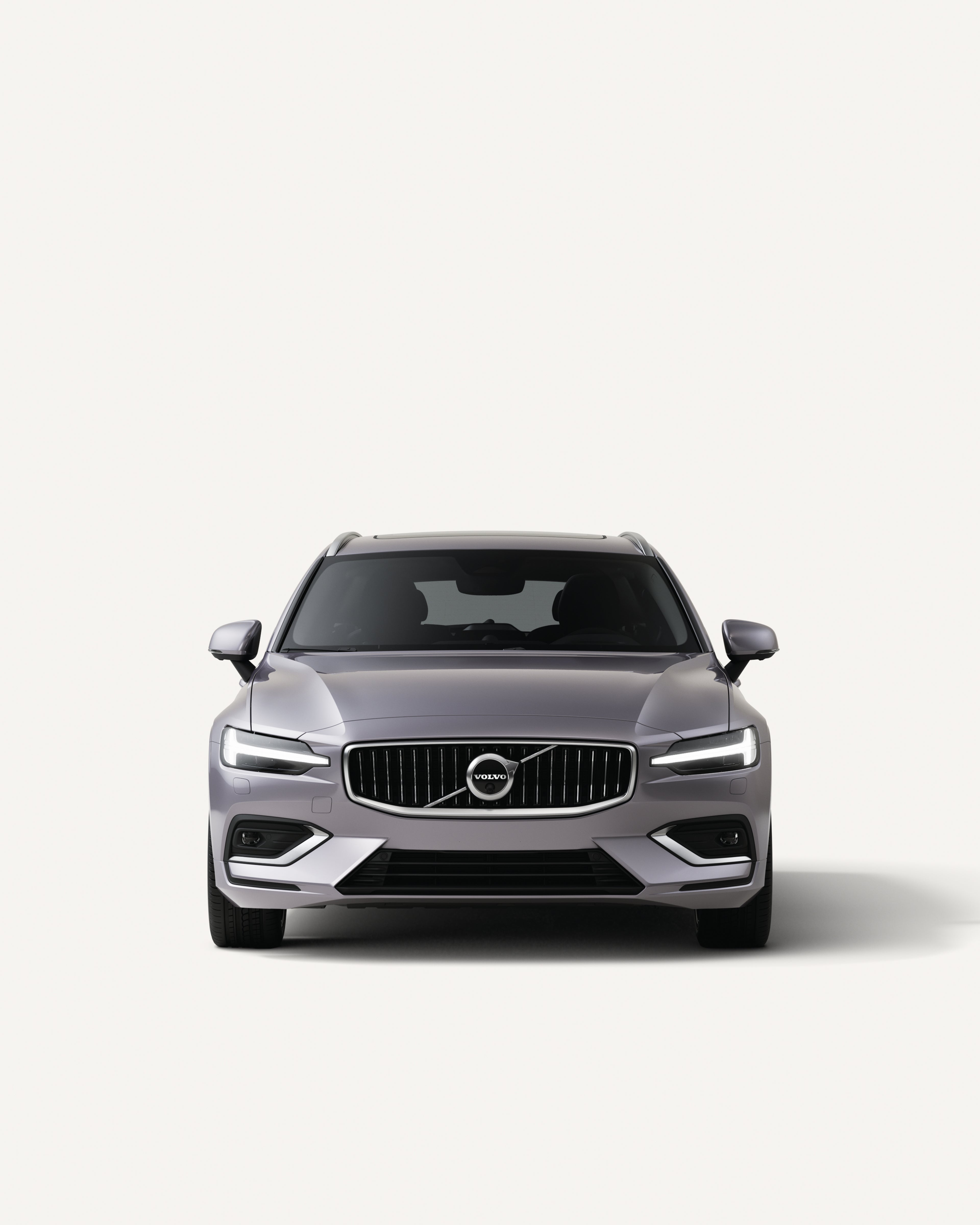 Vue latérale du break familial Volvo V60 semi-hybride dans un studio blanc.